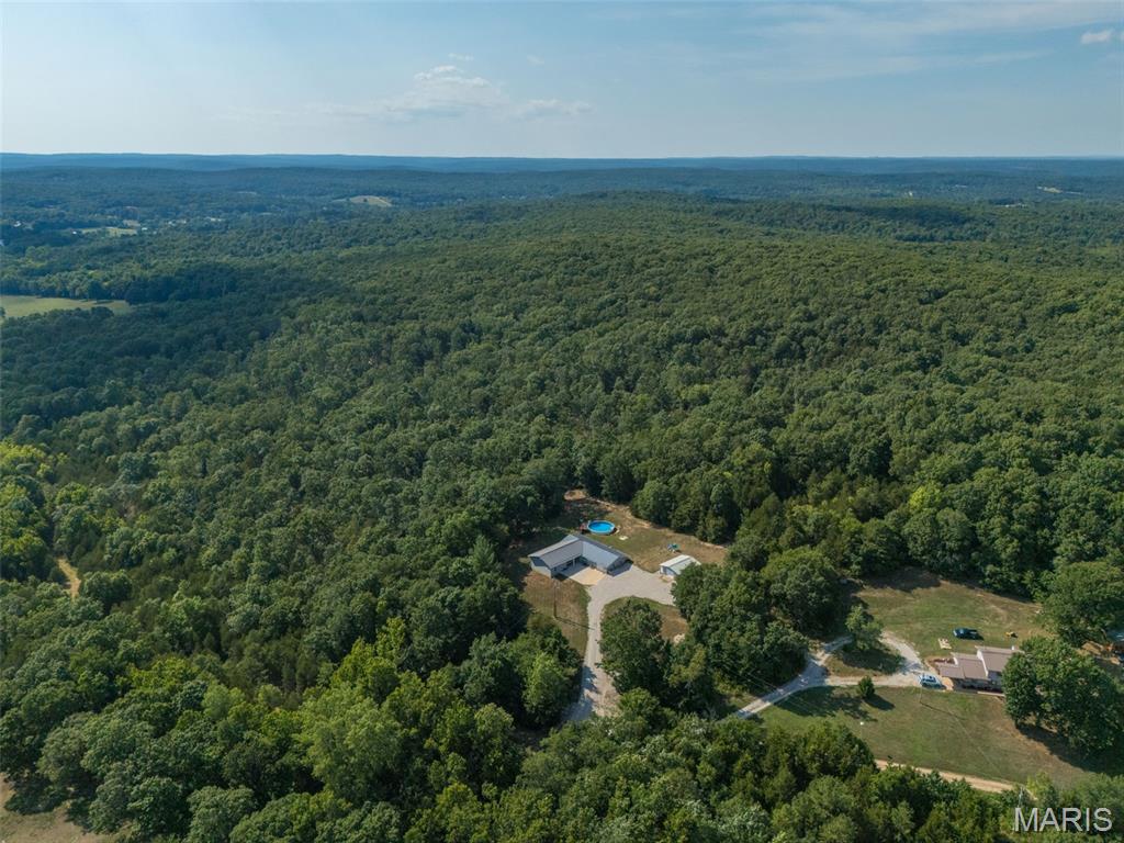 10 UNRESTRICTED ACRES. PRIVACY AND COMPLETE FREEDOM. ONE HOUR FROM ST. LOUIS.
Some properties are just houses. This one is a lifestyle. Tucked away on 10 acres of lush, private wooded land, this is the kind of place people spend years searching for- space to breathe, room to roam, and NO restrictions telling you what you can and can't do on your own land.
Dream big, because it all fits here. Bring the horses. Raise chickens. Watch your kids play in the creek or simply sit on the covered front patio and listen to the water trickle. Plant the garden you've always wanted, there's plenty of open ground and rich soil ready for raised beds, an orchard, or a full hobby farm spread. Hunt your own backyard. Ride ATVs down your own trails. Harvest your own timber, the logging potential alone adds real value to this land. Watch deer and turkey wander through at sunrise, and at night? Starry skies, bonfires with friends, and the peace and quiet you deserve after a long day. This is the space, privacy, and freedom everyone says they want and here it actually comes with the deed.
And the home lives up to the land. Practically rebuilt from the ground up, it features a 1,250 sq ft addition completed in 2020, all-new cabinetry (2020), fresh flooring, and the original 1978 side fully remodeled in 2018. Inside you'll find four oversized bedrooms, three full baths, a bonus room, and a big, open floor plan built for family dinners, holiday gatherings, and everyday living that never feels crowded. The primary suite is your private retreat, complete with a massive full bath hosting a stunning tile walk-in shower.
The major systems? Already handled. Two 2.5-ton HVAC units, a tankless water heater, a new well pump (2020), and a new septic system (2018). This home has been loved, updated, and maintained.  All you have to do is move in and start living.
Summers here are something special. Cool off in your own private above-ground pool (2021), soak up the sun on the wood deck, and host the cookouts everyone will be talking about. And when it's time to work, or play, the 30x30 detached shop is an absolute show stopper: concrete floors, 200-amp electric service, and room for every project, toy, and tool you own. Mechanics, woodworkers, hunters, small business owners, this building was made for you.
Homestead. Hobby farm. Weekend getaway. Forever home. Investment. Whatever you're dreaming of, this property says YES. Land like this doesn't come around often, and it won't wait around either. Come walk the property, breathe the fresh air, and picture your life here. You won't want to leave.