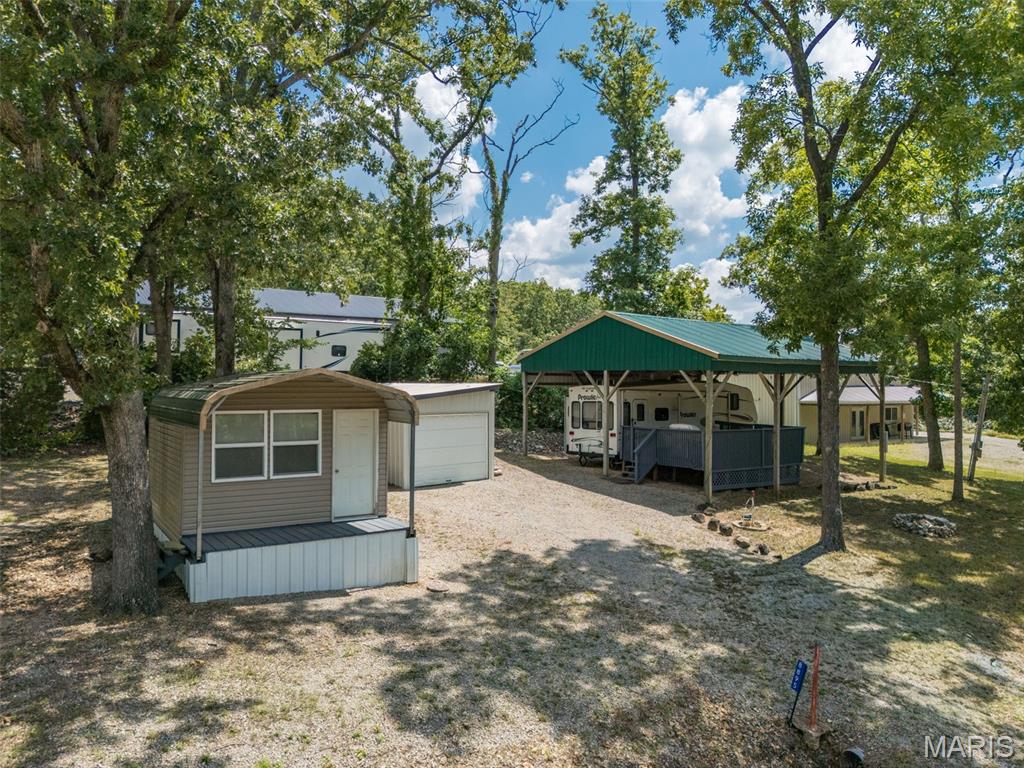 Welcome to lake life at Goose Creek! This corner-lot getaway is perfectly positioned just seconds from the party cove and boat ramp. Making it easy to get out on the water and start enjoying everything this gated lake community has to offer. The property features a cozy 1-bedroom, 1-bath cabin plus a fifth-wheel camper with electric and water hookups. Featuring a large, covered deck, all tucked beneath an oversized carport-style awning for plenty of shaded outdoor living and entertaining space. Enjoy filtered lake views through the trees, a fire pit for those lake nights and plenty of parking for family and friends. Two outbuildings include a larger shed currently used for boat storage plus an additional storage shed for all your lake gear. Property has its own electric, private well and septic holding tank. Whether you're looking for a weekend getaway, summer hangout or your own little place at the lake, this one is ready for new memories!