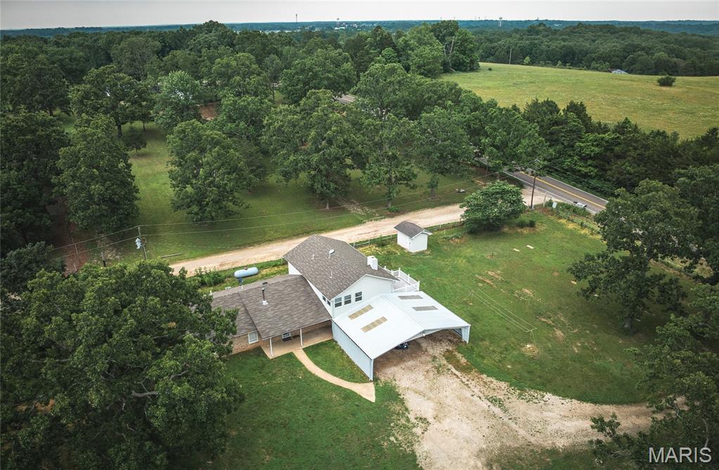 Welcome to this 5 bedroom, 3 full bathroom home set on 6.32 beautiful acres! This spacious home offers over 2,500 square feet of living space and a flexible floor plan perfect for a variety of lifestyles. The main level features 3 bedrooms, 2 full bathrooms, a spacious living room with a wood-burning stove, a full kitchen with a pantry area, a recreation room, multiple storage and bonus rooms, and convenient washer and dryer hookups. The primary suite offers a beautifully tiled bathroom complete with a no step walk-in shower. The upper level provides an excellent extension of living space with 2 additional bedrooms, a full bathroom, a nice kitchen featuring a cooktop, built-in oven, and refrigerator, a comfortable sitting area, a bright sunroom, separate water heater, and additional washer and dryer hookups. With separate exterior access and its own living areas, the layout offers exceptional flexibility for multi-generational living, guests, or extended family. Outside, you’ll find everything needed to start your own homestead. The property includes a 27X38 metal carport with metal trusses, multiple storage sheds, a  lean-to with electric, a chicken coop, garden beds, and dedicated garden space ready for planting. Sellers had a brand new private well installed in 2025! Beautiful landscaping enhances the setting while the acreage provides room for livestock, recreation, or simply enjoying the peaceful surroundings. This property combines rural charm with practical amenities. Whether you’re looking for a hobby farm, homestead, or simply more space to enjoy country living, this property is ready to welcome you home.