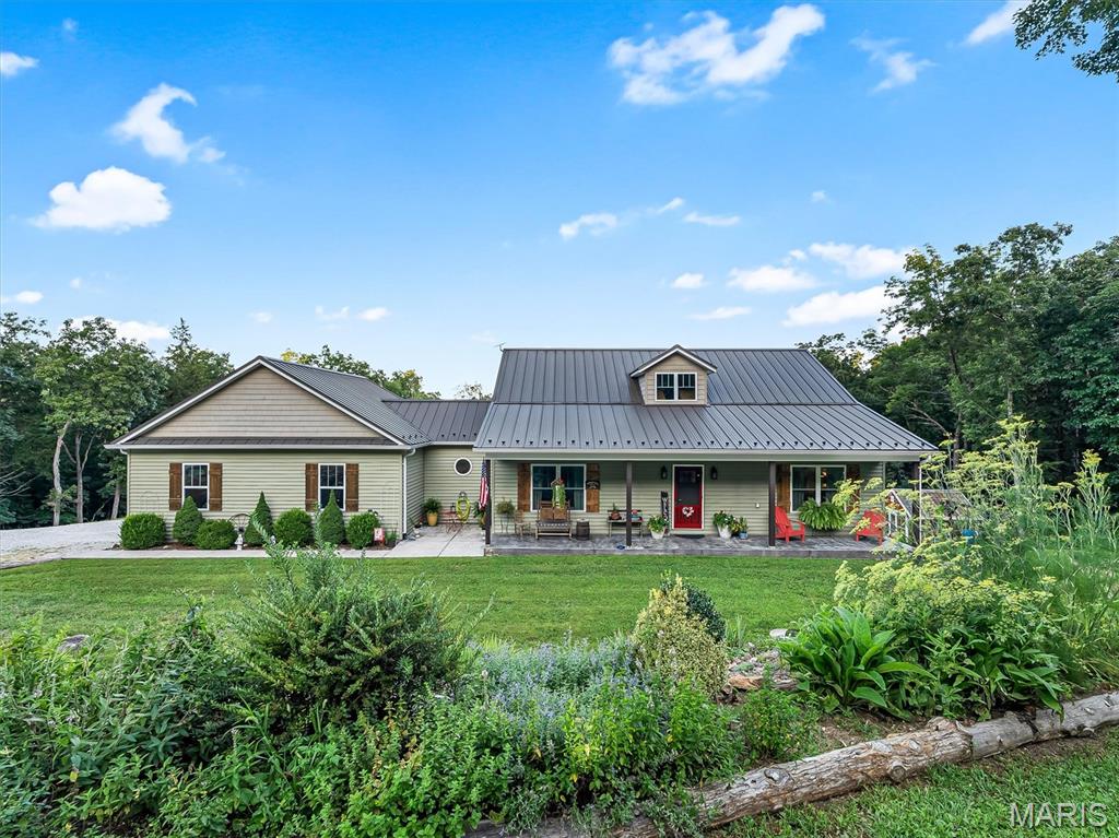 Experience the perfect blend of self-sufficiency, comfort, and country living on nearly **10 picturesque acres**, offering plenty of room to explore, hunt, garden, and enjoy nature right in your own backyard. Designed for sustainable living, this unique property features **15+ established garden beds**, a charming greenhouse, a hand-operated well pump, rainwater collection system, chicken coop, and a spacious **30' x 40' barn**—everything you need to embrace a homesteading lifestyle while still enjoying modern conveniences.
Inside, you'll be welcomed by an inviting open floor plan highlighted by a stunning **double-sided fireplace** that efficiently heats much of the home. The thoughtfully designed kitchen offers abundant storage, complemented by a custom laundry room and an oversized walk-in pantry. The peaceful sunroom is the perfect place to enjoy your morning coffee while taking in the sights and sounds of nature. The finished lower level provides exceptional flexibility with a private studio-style living space featuring a bright bedroom, large custom bathroom, kitchenette, living area, and its own welcoming atmosphere—ideal for guests, extended family, or multi-generational living. You'll also find a dedicated workshop and a whole-house water filtration system for added peace of mind. When it's time to unwind, relax in the hot tub overlooking the beautiful flower gardens or spend a quiet evening on the inviting front porch. Whether you're dreaming of a private country retreat, a hobby farm, or a property where you can live more sustainably while enjoying nearly **10 acres of recreational and hunting opportunities**, this one-of-a-kind home offers a lifestyle that's hard to find.  (Star Link Satellite will remain in Home)