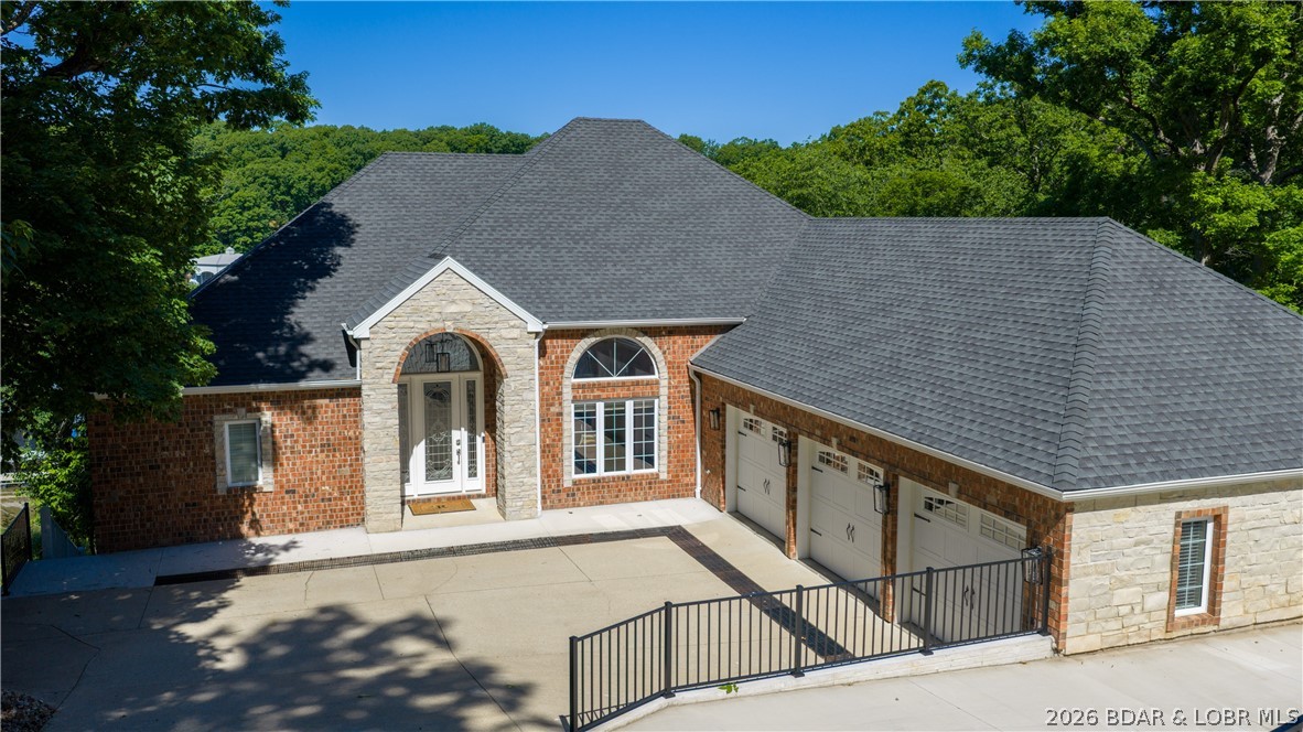 Tucked into a protected cove at the 21 MM in The Villages of Shawnee Bend, this beautiful lakefront retreat offers the complete Lake lifestyle package. Offered partially furnished and updated, this 5-bedroom, 4.5-bath home was designed for entertaining, relaxing, and hosting family and friends. Soaring ceilings, expansive windows, and natural light fill the open main living area, while the remodeled kitchen flows seamlessly into the living and dining spaces. Two bedrooms on the main level, including the spacious primary suite, provide convenient main-level living. The updated primary bath features a tiled walk-in shower, jetted tub, and oversized California closet. The lower level is built for entertaining with a large family room, impressive wet bar, wine and beverage refrigerators, dishwasher, and icemaker. Outside, enjoy outdoor living spaces including large upper and lower screened decks with heaters, a gentle walk to the concrete dock, year-round deep water, 16x36 cruiser slip with 24000# boat hoist, EZ Boat Cover system, and 2 PWC lifts. 3-car garage plus extra parking.