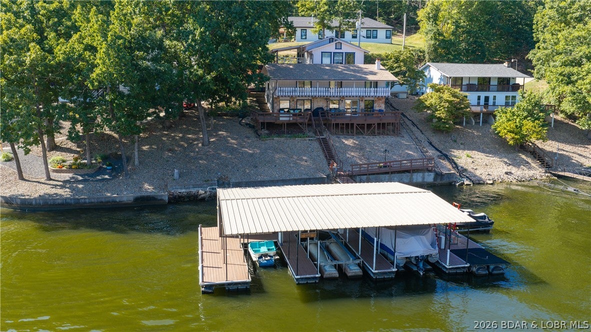 Turnkey lakefront living with a no-wake cove, big lake view, & nearly 2,800 finished SqFt! Located on the 33.5 mile marker, this property offers 2,208 SqFt in the main home plus roughly 600 finished SqFt in the detached garage quarters. The main home features 5 bedrooms & 3 bathrooms, while the garage adds a game room, bedroom, & half bath, bringing the property to 6BR/3.5BA. A detached 2-car garage & carport provide plenty of covered parking & storage. Enjoy a protected no-wake cove while still capturing a big lake view. The 3-well dock offers plenty of room for your lake toys, & the home comes turnkey with furniture included. The annually maintained tram provides zero-step access from the garage to the home & all the way to the lake! Recent improvements include a new roof in 2023, furnace & exterior paint in 2024, deck & dock wood replacement in 2025, & new A/C plus stained deck & dock in 2026. Additional updates include gutters & LeafFilter, with new garage & guest room windows plus a family room sliding door already paid for & scheduled for installation. Space, updates, easy lake access, & a fantastic setting make this the complete Lake of the Ozarks package.