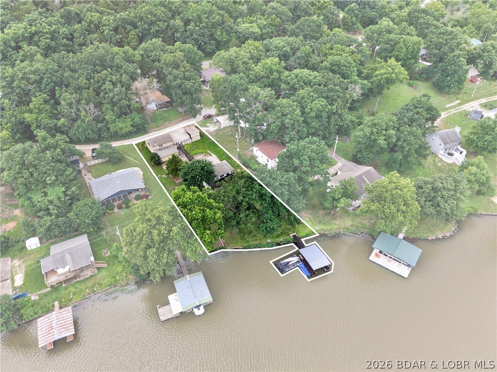 Step back to simpler times with this nostalgic Lake of the Ozarks cabin nestled on 100 feet of shoreline at the Big Niangua 15MM. Enjoy a gentle walk to the water and a prime location just around the corner from Ha Ha Tonka Cove, known for some of the clearest water on the lake. Lovingly maintained, this 3-bedroom, 2-bath retreat is move-in ready with numerous updates, including a newer roof, new HVAC (2025), laminate flooring, and a new septic tank (2020). The main level offers two bedrooms, a full bath, laundry, kitchen, and an inviting living area that opens to a covered lakeside deck. The walkout lower level features a third bedroom, full bath, crawl space access, and a covered patio. At the water, enjoy your private dock with a 10x24 slip, drive-on boat lift, and PWC lift. Ample parking includes a stick-built carport and detached two-car garage.  All this conveniently located just minutes from Camdenton and surrounded by the beauty of Ha Ha Tonka State Park, this is the perfect affordable lake getaway to start making memories that will last a lifetime.