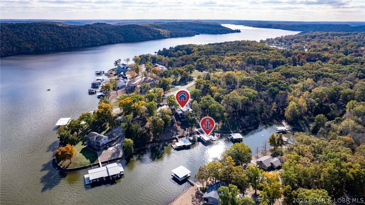 Best-value opportunity in custom new-construction lakefront living—now made even more compelling with an additional 7-acre parcel included nearby. Never lived in and impossible to duplicate at this price, this architecturally designed residence offers rare zero-step dock access, premium construction, and a level of finish seldom found on the Lake. Soaring vaulted ceilings, rich hickory flooring, and dramatic 8-foot sliding glass doors frame peaceful cove surroundings with beautiful main-channel views. The chef’s kitchen was built to impress with custom cabinetry, quartz surfaces, professional-grade appliances, and a massive 12-seat island. Two private en-suites offer spa-level baths and custom walk-in closets, while heated lower-level floors, indoor and outdoor fireplaces, wine cellar, and spray foam insulation deliver year-round luxury and efficiency. Over 2,000 square feet of covered and open patio space extends the entertaining outdoors. Private dock includes 12x34 and 10x34 slips, swim platform, and storage shed. Seller now includes a separate 7-acre parcel ideal for shop, guest home, or future build—adding flexibility, privacy, and long-term value rarely found in one package.