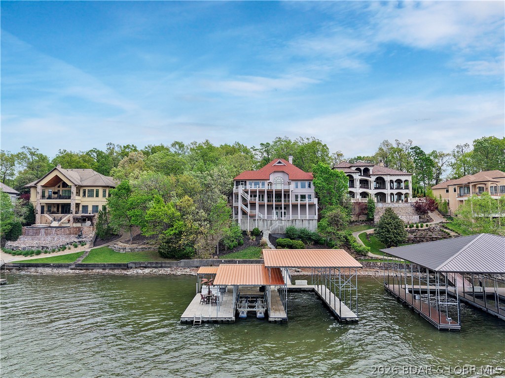 Completely updated from top to bottom, this luxury lakefront home in the gated Villages Subdivision feels entirely brand new. With all-new flooring, interior & exterior paint, a redesigned kitchen, updated bathrooms & vanities, modern fixtures, appliances, gutters, & fresh landscaping, no detail was overlooked. Located in a gated community on a gentle lot the home offers stunning 20MM views with plenty of outdoor entertaining space. The home is massive with 6,000 SF of living space, including six private en-suites, including a custom bunk room. The open main level features a gourmet kitchen that flows to a spacious deck and screened porch—perfect for year-round grilling. The lower level impresses with a full bar, glass-walled wine cellar, and lakeside living area that walks out to a covered patio. The oversized concrete dock site in a protected deepwater cove, and includes 18'x48' & 12'x34' slips, a boat hoist, & dual PWC lifts. There’s even space for a future pool (See Attachment with Pool Renderings). This completely refreshed home blends luxury, comfort, and lake living at its finest. By land or water this stunner is minutes from the best the lake has to offer.