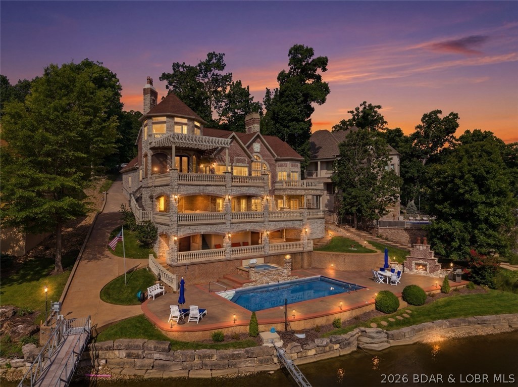 Iconic & class throughout this incredible Lakefront Estate, featured in all the Porto Cima Brochures during creation of this subdivision!  Architecturally, this property boosts stone & brick exterior with stamped concrete decks, wood ceilings throughout & numerous balconies to take in this historic cove.  Incredible dock envelope for unobstructed views, 3 well concrete dock with all the bells & whistles or relax in your Saltwater Resort Style pool & spa on the water's edge including outdoor bar & grill, multiple fireplaces, fire bowls, waterfalls & sound system. The interior showcases a Gourmet Chef's kitchen with 2 pantries & Sub Zero/Wolf Appliances, Main Level living, dinning areas, a Great room & Primary Suite second to none!  Don't worry about steps with a full elevator to all three levels & gigantic cart path to access the dock, pool & additional lower level garage.  Upper level features a bedroom/bathroom, a breathtaking Turret office & a killer Mezzanine!  The Lower level is perfect for guests with 3 en Suites, additional bunkroom, tons of storage & large family room.  This Smart home has so many upgrades to mention like geothermal, check out feature sheet for details.
