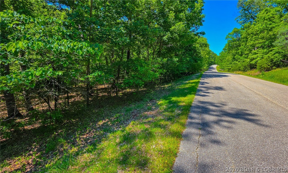 Nestled in the prestigious community of Porto Cima along Spring Creek Drive, this exceptional 0.42-acre lot offers the ultimate canvas for your dream home, boasting a remarkably level, builder-friendly topography surrounded by a serene canopy of mature trees. Positioned just steps from the water, the property features direct lake access via a community path right behind the lot, allowing you to effortlessly enjoy the Lake of the Ozarks lifestyle alongside peek-a-boo lake views. Beyond its premier location, ownership grants you full access to Porto Cima’s amenities, including community pools, playgrounds, a fully equipped exercise room, and more. Combining natural privacy, a rare flat building footprint, and premium resort perks, this lot is a standout opportunity to build your ideal lakeside retreat.