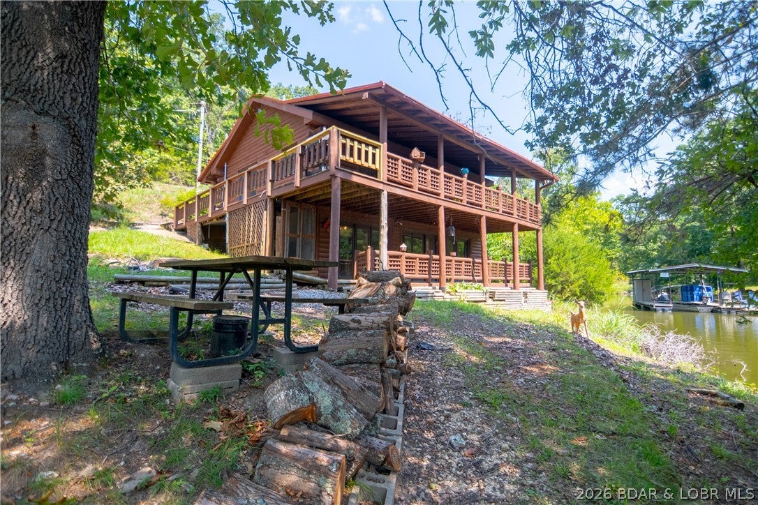 This is what a lake cabin is supposed to feel like! Tucked away in a quiet, protected cove at the 53 Mile Marker, this charming 3-br lakefront log home delivers the rustic character, privacy and easygoing lifestyle buyers come to Lake of the Ozarks looking for. From the moment you step inside, vaulted ceilings & warm wood from floor to ceiling create an authentic cabin atmosphere. The main level features the kitchen, living room and primary suite with cedar-lined closet, double vanity & walk-in shower. Downstairs offers a second kitchen, family room and 2 additional bedrooms—an ideal setup for family, guests or multiple generations to enjoy their own space.  Relax on the covered roadside porch or choose from 2 levels of covered lakeside decks overlooking the peaceful cove. The gentle lakefront setting provides an easy walk to the dock with hardly any stairs. A metal roof, detached 2-car garage and workshop below provide plenty of room for vehicles, lake toys & projects. Private, peaceful and full of character, this is the kind of place where weekends slow down, mornings are spent on the porch & days end by the water. If you're looking for an authentic getaway, you've found it.