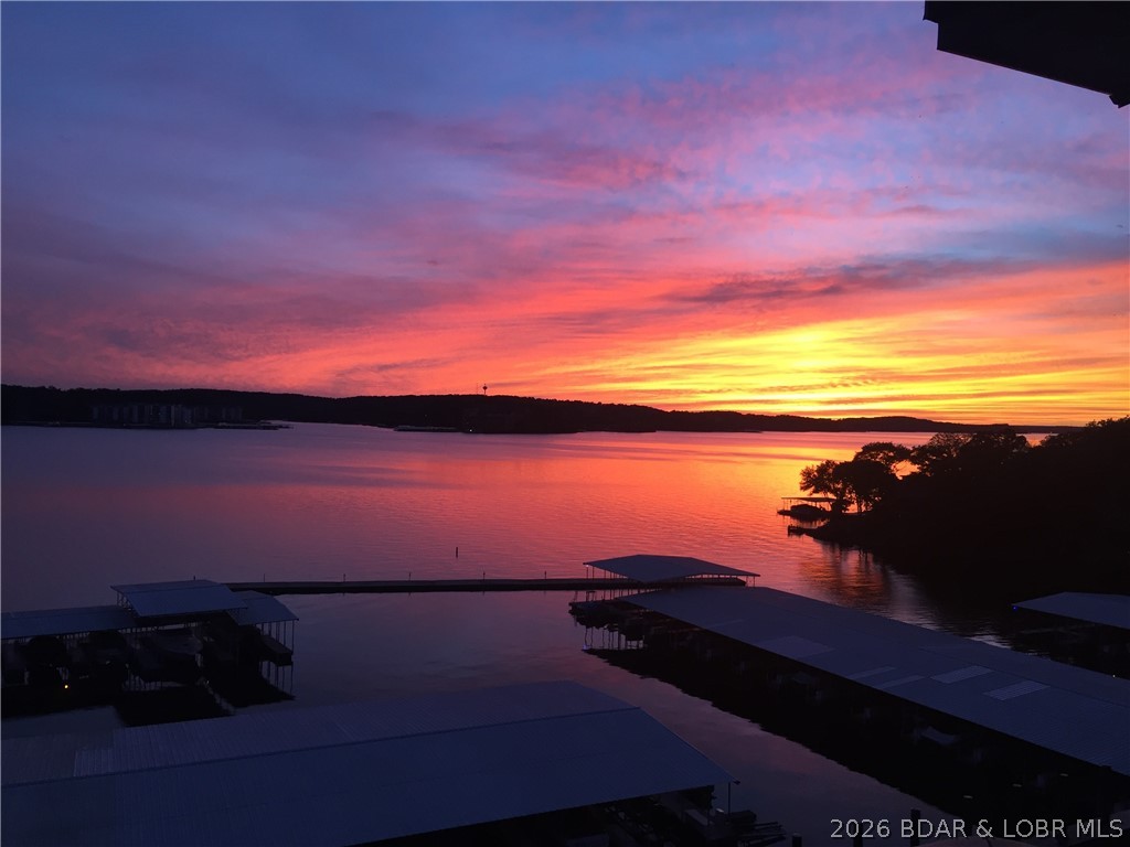 This view will NEVER get old!! Any time of day whether it's morning coffee, quick lunch or evening drinks, you can enjoy this incredible panoramic lake view…from your primary bedroom, living room or covered deck! Vaulted ceilings makes this 3 bed 2 bath top floor unit live large. Open concept allows everyone to gather in the living/dining/kitchen with easy access to covered deck. The lakeside master suite offers privacy and spectacular views. Two additional guest bedrooms with shared bath and functional laundry complete the package. You have the perfect view of your 12x28 slip from your deck and you are only a short walk to the resort-style pool or quiet peaceful second tier pool. The complex additional amenities include club house, tennis/pickleball court, lakeside boardwalk, boat trailer parking, and playground. Great for full time living, vacation home or investment property. The prime location is just minutes away from the Bagnell Dam strip, restaurants, and shopping making it perfect for full time living, vacation home, or investment property. Come take a look!