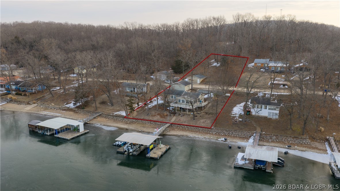 Don’t miss this wonderful lake home located at the 8-mile marker in the coveted North Buck Creek Cove, offering awesome lake views and only six steps down to the water. The main level features three bedrooms, one bath, an updated kitchen, dining area, and an inviting living room that walks out to a large deck overlooking the lake. The lower level offers a cozy family room with a wood-burning stove, full bathroom, wet bar with refrigerator and sink, and walk-out access to a covered patio facing the water. Also on the lower level is an additional studio apartment with its own entrance, complete with a fourth bedroom, full bath, and living area. Easy on the knees best describes the gentle walk-out to the covered patio and the smooth, gradual walk to the dock. You’ll love the two detached garages with room for up to four cars, multiple storage buildings, and plenty of parking for family and friends. There’s also room to grow with a second-tier lot across the street that includes an additional two-car garage. A Brand New Roof was just installed and City Sewer will be hooked up soon.  This property would make a fantastic investment opportunity, Vacation Retreat, or full-time lake home.