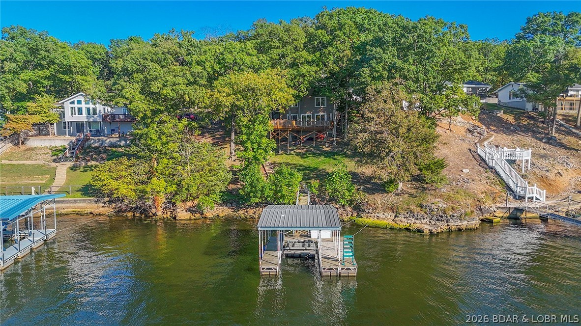 Relax, enjoy and make up for lost time! Embrace the new normal with family and old friends spending time on the large lakeside decks and enjoying the expansive views. This 3 Bed/2.5 Bath home boats a generous 1,668 sq ft of living space, 90ft of lakefront, deep water & stunning main channel views! Lower Level features 1/2 bath, an eat-in kitchen, formal dining area, huge laundry room & spacious living room with wood-burning fireplace. The upper level features 2 Guest Bedrooms, 1 Full bath and Lakeside Primary Ensuite featuring loft with additional sleeping area, Large walk in custom tile Shower. Gentle driveway with good parking and room to build a garage. Conveniently located off KK, this home offers easy access to dining, mini golf, & shopping. The gentle lot leads to a private single well dock. Situated at the 24 mm, you're close to lake favorites like Paradise & Margaritaville! Check out our virtual tour for a birds eye view!