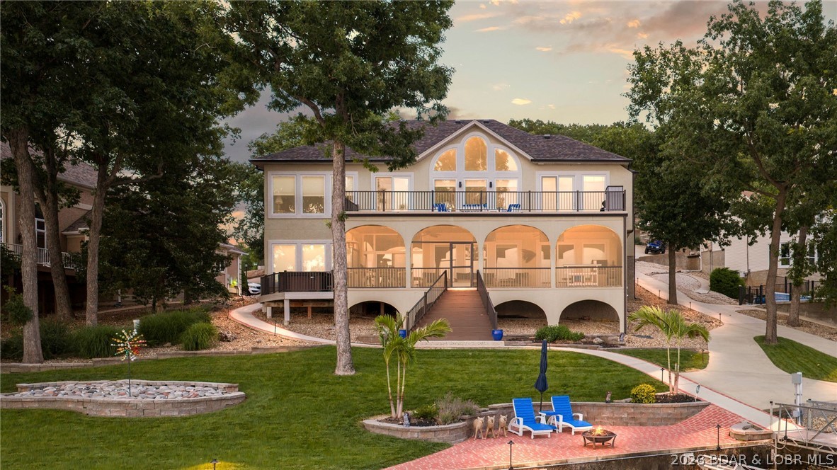 Experience exceptional lakefront living at this beautiful property in the prestigious Four Seasons community. Situated on 137 feet of prime Lake of the Ozarks shoreline, this stunning 4-bedroom, 3.5 bath residence offers approximately 4,300 square feet of thoughtfully designed living space with breathtaking main channel views. Recently updated with a new roof, refreshed stucco, epoxy garage floors, new deck railings, and professional landscaping, the home seamlessly blends luxury and comfort. The open-concept floor plan features vaulted ceilings, a spacious living area with fireplace, a gourmet kitchen, walk-in showers, jetted tub, wet bar, and a finished walkout lower level ideal for entertaining. Outdoor living is equally impressive with expansive decks, a screened porch, patio just steps from the water, and direct access to a private dock featuring two boat slips and a 4 PWC slips with lifts. Custom boat dock built for main channel living with a heavy duty C-Channels, concrete trays, and anchored to the ground! Located within the sought-after Four Seasons community, owners enjoy access to pools, playgrounds, walking trails, gym & premium amenities.