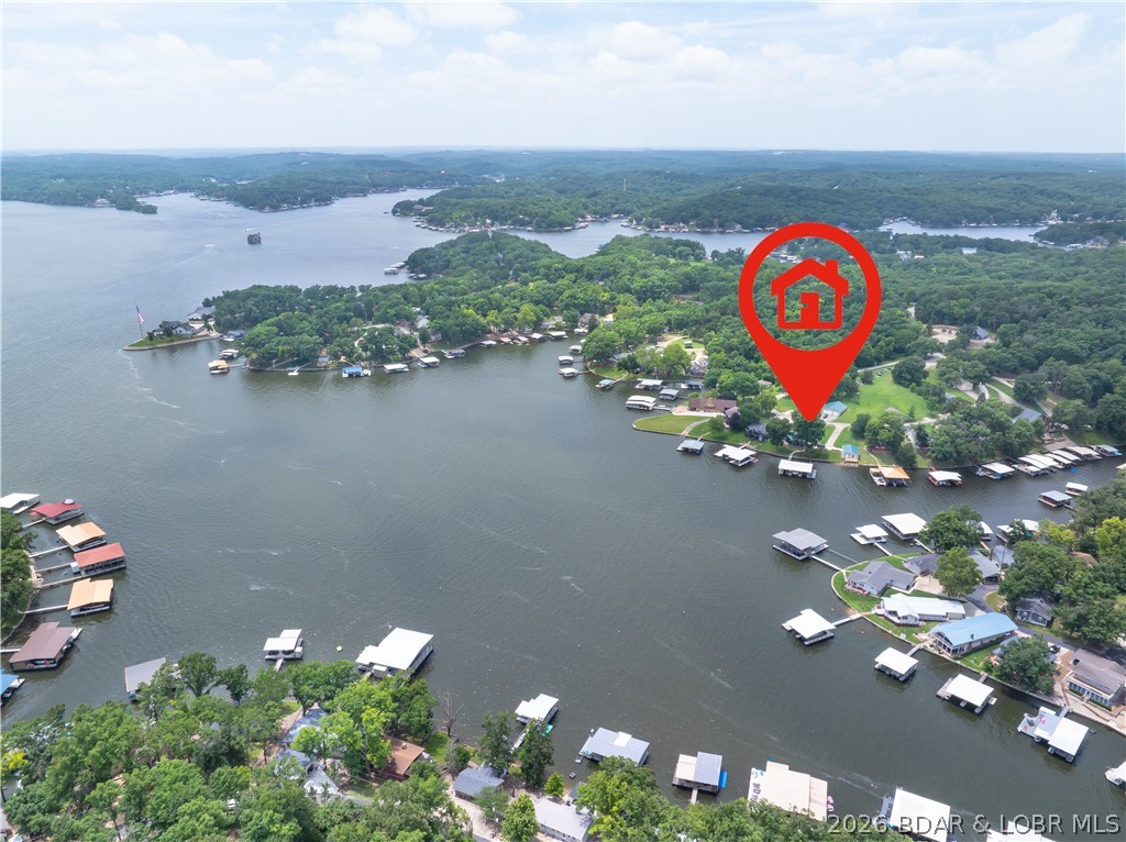 Enjoy 160' of gently sloping lakefront with just 9 easy steps from the 3-slip dock to the spacious screened porch. The dock offers 20 feet of water depth at the slip openings, while the setting provides stunning, layered views from the peaceful cove to the main channel at the 7 Mile Marker of the Osage. Located in a meticulously maintained neighborhood, the HOA offers exceptional amenities including a private water system, boat ramp, boat trailer parking, community gathering areas, and trash service. Designed as a forever home, this property was completely remodeled down to the studs with quality and longevity in mind. A private guest house provides ideal accommodations for family and friends, while the 1,200 sq. ft. tandem 3-car garage includes a climate-controlled workshop. With room to expand living space, add garage or RV parking, or enlarge the dock, this property offers endless possibilities. Bonus-Long term rentals allowed! This ideal property would be perfect for full/part time living as well as allowing you to make additional income. Check out this amazing estate!