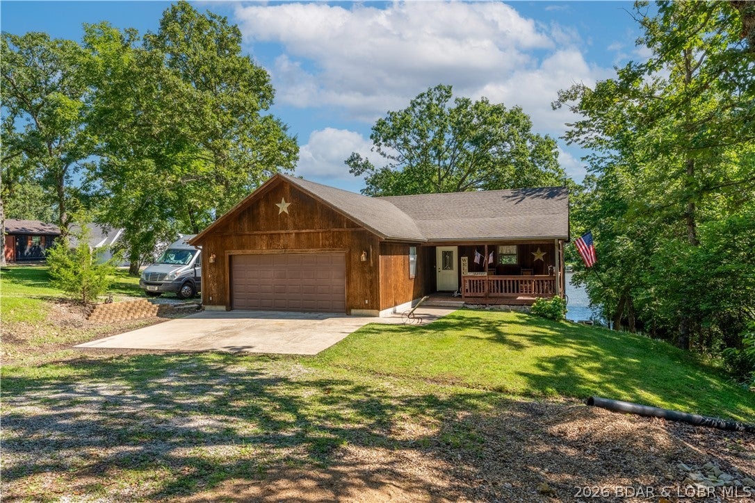 Discover lakefront living at this custom-built waterfront home in a protected cove at the 84-mile marker of the Lake of the Ozarks, just outside Warsaw. Built in 2006 and used only seasonally, this meticulously maintained home offers 2,235 finished sq. ft. with 3 bedrooms, 2.5 baths, an attached 2-car garage, and an open floor plan with a finished walkout lower level leading to a spacious lakeside patio. Enjoy a private covered 1-slip dock with quick access to the main channel. The property includes two waterfront lots plus an additional approximate 1-acre lot across the road, ideal for a future storage building, workshop, or garage. An RV parking pad with electrical hookup adds convenience for guests or recreational vehicles. The home is prewired for high-speed internet, whole-home audio, telephone, and security systems. Whether you're looking for a weekend getaway or a year-round residence, this property offers quality construction, privacy, additional land, and excellent waterfront access on the quieter side of the Lake of the Ozarks.