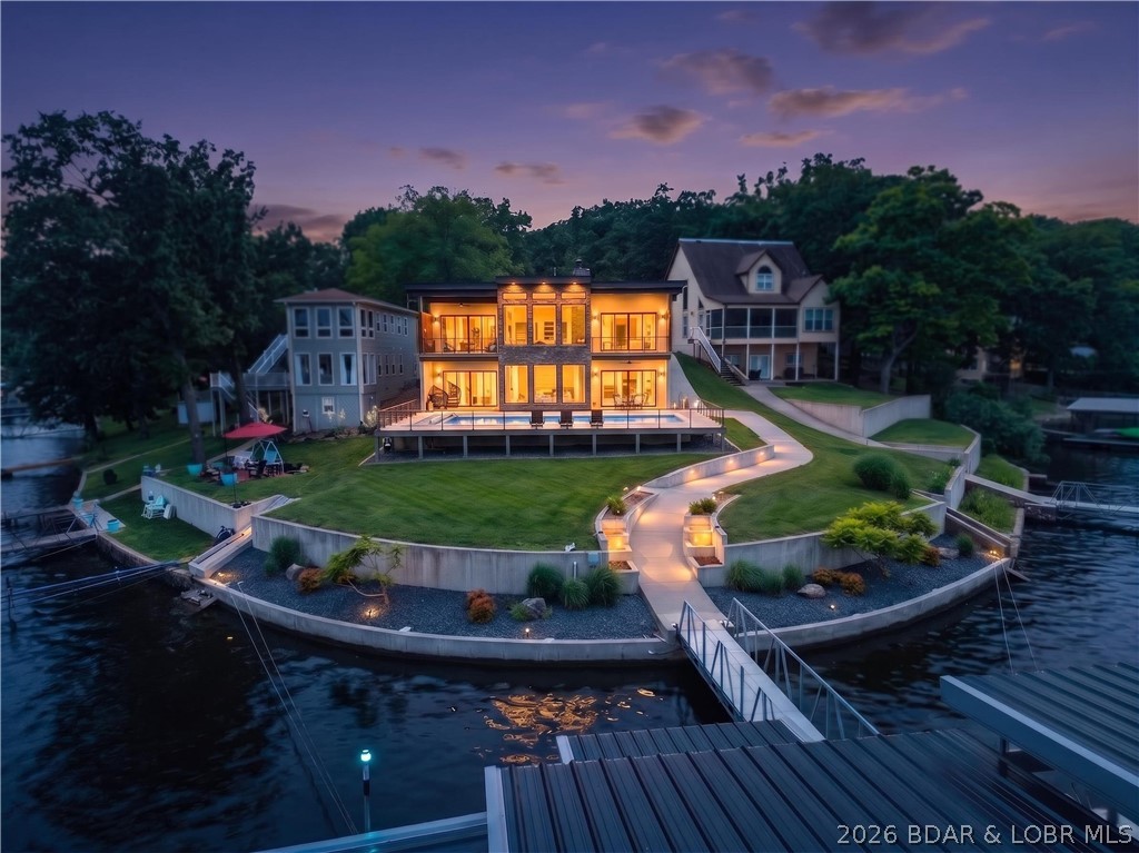 Fully furnished and move-in ready, this exceptional contemporary waterfront estate delivers the ultimate Lake of the Ozarks lifestyle. Positioned on a point lot with panoramic main-channel views and protected cove waters, this 5-bedroom, 6-bath residence offers over 4,500 square feet of luxury living, including a 2-car garage with epoxy flooring.

Walls of glass showcase lake views throughout, while the walkout lower level features radiant heated flooring and opens to outdoor living spaces. The 16' x 42' heated in-ground pool with an automatic cover creates a resort-style setting.

The waterfront features a concrete seawall, concrete walkways, and a dock with multiple boat hoists, two PWC ports, a swim platform, and automatic boat covers designed for a 2025 Cobalt R35 and 2021 Premier Tritoon. The dock, hoists, and PWC ports are included with the sale.

Nearly all furniture, furnishings, TVs, and electronics convey with the property, excluding only personal items, two recliners, and the rocking chair in the primary suite. The 2025 Cobalt R35, 2021 Premier Tritoon, and Sea-Doo are available for purchase separately, creating a turnkey package. Experience premier lake living.