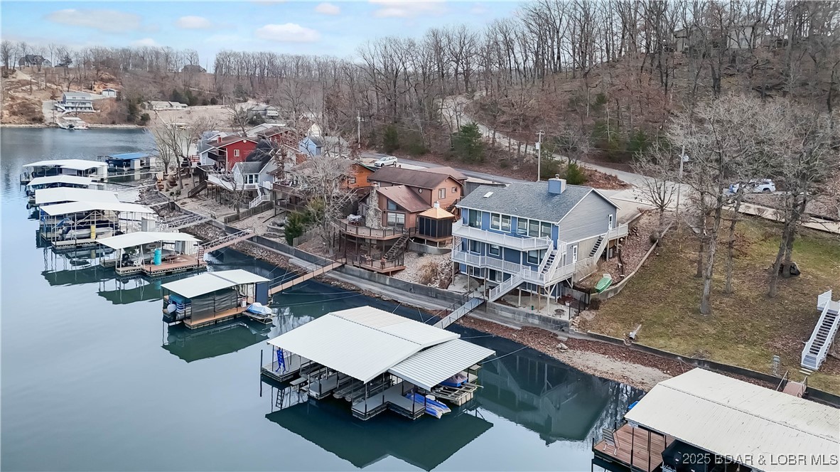 BACK ON THE MARKET!!  Well-maintained waterfront home located in a quiet cove at the 2-mile marker of the Niangua Arm, offering a peaceful setting with quick access to open water. Blacktop access leads to the home, with an attached two-car garage and additional parking for guests.  The main level features a vaulted great room with fireplace and lake views, an eat-in kitchen with granite countertops, and low-maintenance composite decking designed for easy outdoor living.   All bedrooms are located on the middle level and offer lake views, along with two full baths and a convenient laundry area. The primary suite includes a walk-out, creating a natural connection to the outdoors. A finished lakeside game room with exterior access provides flexible space for a bunk room, hobby area, or additional entertaining.
An easy walk leads to a two-well dock with swim platform, covered PWC slips, Wet Steps, and approximately 18–19 feet of water under the dock. A concrete seawall is already in place. New roof installed 12/26/25. Boat lifts available separately.  New septic tank being permitted (DNR) to be installed by Central Septic. Call Margie for details.