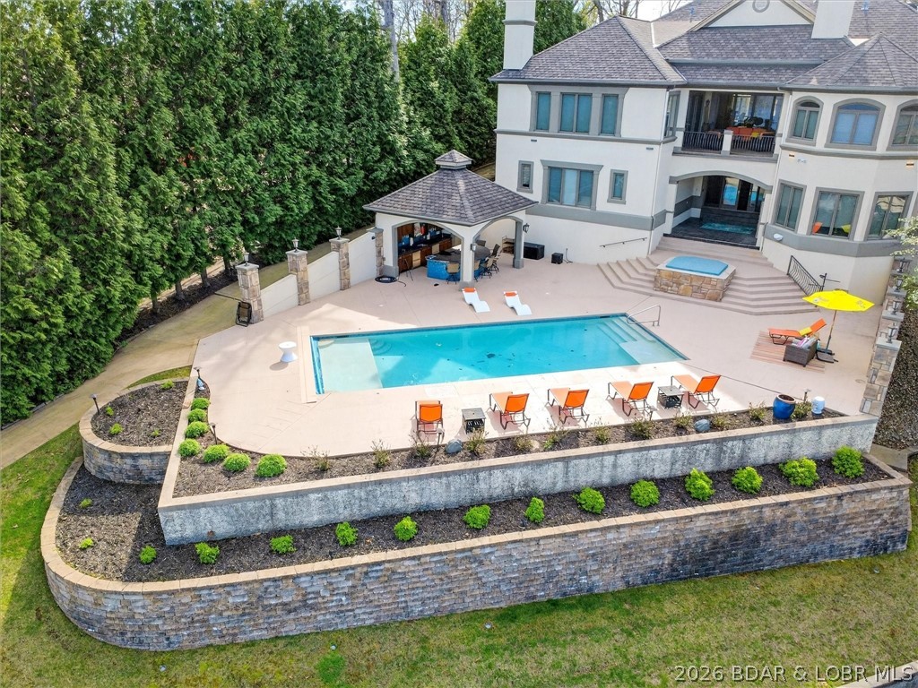 Located in Porto Cima at Lake of the Ozarks, this exceptional waterfront estate offers luxury living and an unbeatable lifestyle. Featuring 5 en-suite bedrooms, a gourmet kitchen with Wolf & Sub-Zero appliances, open-concept living on both levels, a stunning architectural staircase, main-level primary suite, built-in office, and expansive lower level with family room, wet bar/2nd kitchen, billiards and gaming area, and 3 en-suites. Enjoy breathtaking main channel views from nearly every room.Outdoor living shines with a private pool, hot tub, fire pit, bar area, and full outdoor kitchen—perfect for entertaining. The 42x62 dock includes a 18x54 boat slip, 12x12 PWC lift for 2, private wave breaks, 2 wet steps, 6x12 shed with roll-up door, and Touchless boat cover. Gentle walk to the dock.Additional features: 3 kitchens, 3 laundry areas, 5 fireplaces, elevator, custom cabinetry, and a 3-car garage. Turnkey and ideally located near the Bagnell Dam Strip, by water across from Backwater Jacks and near Dog Days—close to top dining, entertainment, and family-friendly destinations. Ask your Realtor about the boat available.