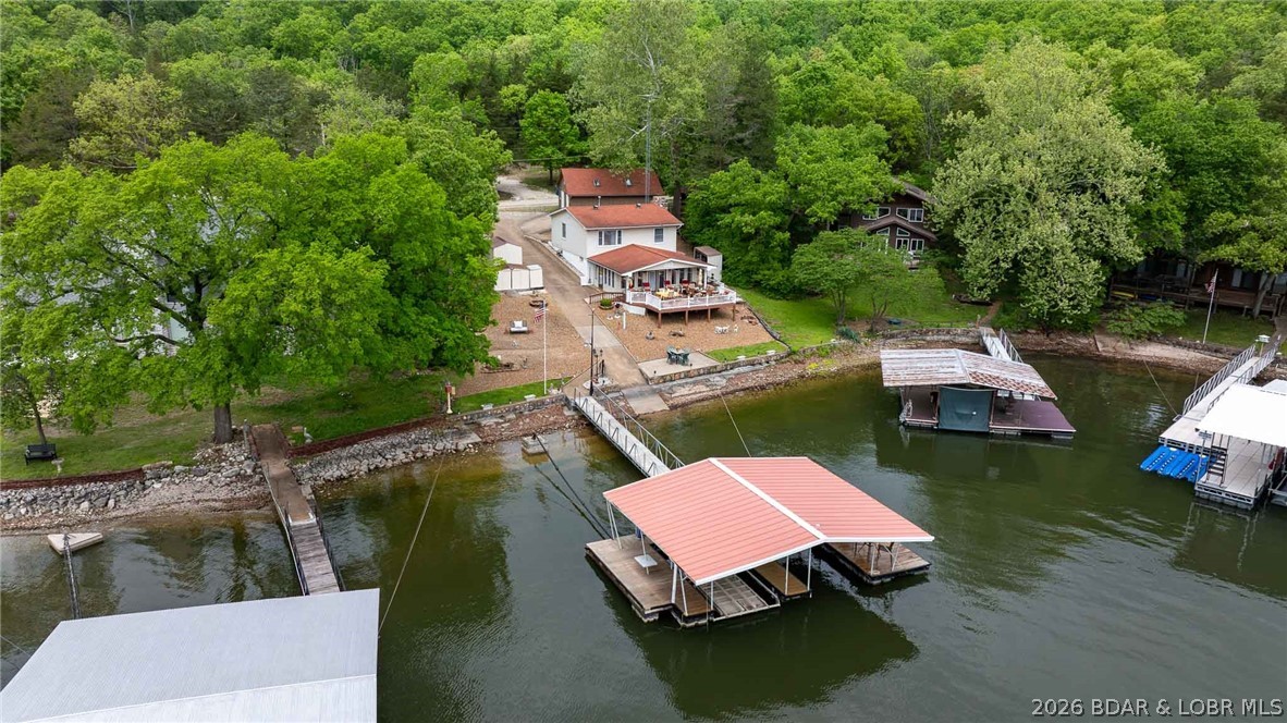 Gentle lot. Easy steps. Big view. If you’ve been waiting for that “checks all the boxes” lake place…THIS IS IT. Located at the 2MM of the Gravois Arm, this 3 bed, 1.5 bath home offers 90’ of shoreline, a gentle lot, and a quick, easy walk to your 2-well dock with swim platform—no steep hikes here. The main level is designed for lake life—open and inviting with a fireplace, bar area, kitchen, dining, and a wall of windows that pull in natural light and showcase those panoramic lake views. Step out to the spacious deck and you’ve got the perfect setup for entertaining, dining, or just relaxing after a day on the water. Upstairs features a roomy primary bedroom with two closets (including a walk-in), two guest rooms, plus a den/office that could easily serve as extra sleeping space. The full bath has been beautifully updated with a walk-in shower. A 30x30 detached 2-car garage and tons of parking make hosting friends and family easy. Cove location for protection, main channel views for the vibe, and easy access by land and water. This is the kind of property people wait for—and they don’t come around often. Don't miss out, schedule your showing today before it's too late.