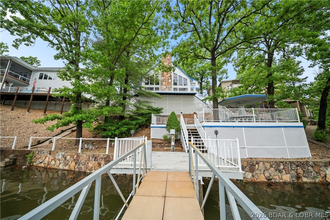 Discover a rare opportunity to own a truly distinctive lakefront retreat that breaks the mold of the typical modern lake home. This spacious 4-bedroom, 3.5-bath home is filled with character, timeless charm, and unique architectural details throughout, offering the perfect canvas to bring your personal vision to life. With great bones and an inviting layout, this property is ideal for entertaining and making lasting lake memories. Seller is offering a 5,000 flooring allowance. The oversized master suite is a true escape, featuring a massive bedroom and an expansive en-suite bath complete with a large soaking tub and walk-in shower. Enjoy 3 levels of entertaining space, including a private lower-level bedroom perfect for guests, a sauna, one-of-a-kind bar area, and a stunning floor-to-ceiling stone fireplace that anchors the main living area. Step outside to the spacious back deck and soak in beautiful lake views. The brand-new covered and uncovered dock features 2 boat wells and easy water access. Located in a protected cove within the State Park, you’ll enjoy privacy, calm waters, and an unbeatable lake setting. Garage included for extra storage and lake essentials.