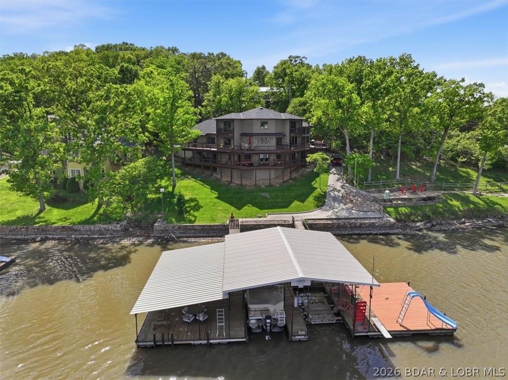 Vaulted ceilings, walls of windows, and wood-burning fireplace set the tone for this luxury lake home designed to capture the outstanding views from every room! Offering main level living, the layout is both functional and inviting, with a kitchen that features an island, pantry, and seamless flow into the dining area and stunning living room. The primary suite offers a walk-in closet, jetted tub, and walk-in shower. Upstairs, two bedrooms each have private balconies, walk-in closets, and share a Jack-n-Jill bath. The lower level is built for entertaining with a second living room, wet bar, bedroom, storage/safe room, and a full bath with direct deck access—perfect for coming in off the lake! Covered and uncovered decks create tons of outdoor entertaining space and zero effort to dock using the cart path! Two 10x28 slips, (2) PWC slips, swim platforms on both sides, a slide, ladder, fishing cleaning area, AND all lifts included! 260ft of shoreline with cove protection, big main channel views, and deep water year-round! Parking and storage are unmatched with a 2-car garage, detached garage, and a 36x44 insulated shop w/ mini split! Set on 1.3 acres with pavement to the door, NO hoa!