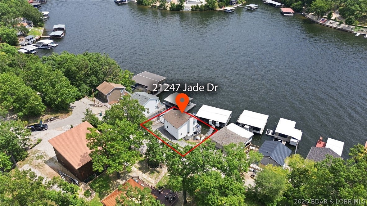 INVESTORS TAKE NOTE! DEEP WATER COVE! LARGE 3-WELL DOCK! Wake up to breathtaking easterly views from this sell maintained 3-bed, 3-bath lakefront home, perfectly positioned in a protected cove at the 5 Mile Marker. The open-concept main level takes full advantage of the incredible setting w/ soaring vaulted ceilings, a wall of lakeside windows framing panoramic water views, a cozy wood-burning fireplace, wet bar, designed for entertaining. The private upper-level primary suite offers a peaceful retreat complete with its own lakeside balcony, while the walkout lower level features a spacious family room ideal for guest. Multiple decks provide plenty of room to enjoy morning coffee, evening grilling, and the ever-changing views of the lake. At the water, the included 3-well dock w/10x28 slips plus a PWC lift, offering exceptional space for boating and lake recreation. With its protected cove setting, expansive main channel views, versatile layout, and impressive dock setup, this property offers an outstanding opportunity at Lake of the Ozarks. New HVAC. This lovely row of houses is primarily vacation rentals so proven popularity with vacationers! SEE Rental Projections attached.