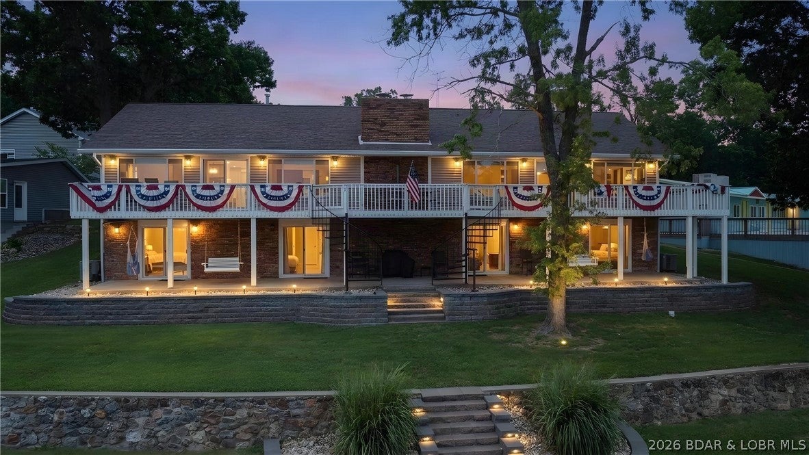 Experience elevated lake living with exceptional space, flexibility and proven income potential on the Gravois Arm. Currently operating as a successful 5-star short-term rental, this beautifully remodeled main house offers 4 bedrooms and 6 baths across two complete living areas that can function separately or open into one expansive retreat—ideal for a large family, multigenerational getaway or continued short-term rental investment. Panoramic main channel views, high-end finishes, exposed beams and generous gathering spaces create a refined yet relaxed atmosphere. You'll appreciate that all bedrooms feature a private ensuite. An added bonus, a separate studio-style cabin with a bedroom, full kitchen and full bath provides even more privacy for guests or additional rental potential. Enjoy spacious decks overlooking the lake, a level lot with easy access to the large dock, three boat slips with lifts and two PWC slips with lifts. With paved roads, abundant parking and room for everyone to gather while still enjoying their own space, this property is designed for unforgettable lake days and offers a proven, compelling investment opportunity. Schedule your showing today!