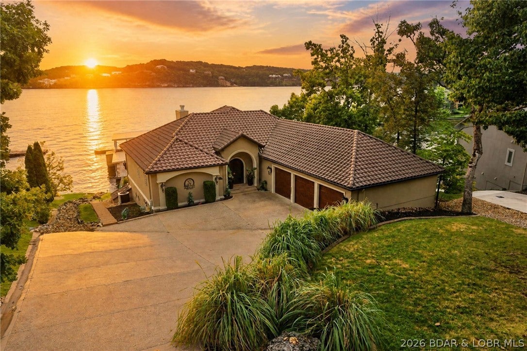 This custom estate is the pinnacle of lakefront luxury. Nestled within the prestigious Jack Nicklaus Signature golf community of Porto Cima, this 5-bedroom, 4 full/2 half bath sanctuary offers an unparalleled blend of artisanal craftsmanship and resort-style entertainment. Every inch of this masterfully designed home is positioned to frame spectacular, panoramic main-channel views. The gourmet kitchen features exquisite Knotty Alder cabinetry, granite countertops with sanded raw edges, and a Dacor gas cooktop. Artisanal detailing continues throughout this spectacular home with unique custom stone, wood flooring, solid wood doors, all highlighted by 12- and 14-foot ceilings. Enjoy the ultimate vacation lifestyle from your private, custom lakeside gunite pool, complete with built-in bar stools—the perfect vantage point to relax and watch the boating action unfold. For ultimate convenience while entertaining, the outdoor space features a dedicated exterior half bath, keeping pool traffic outside and your interior pristine. Warm, inviting, and overflowing with bespoke features, this home brings a smile at every turn. A must-see; experience this exquisite home today.