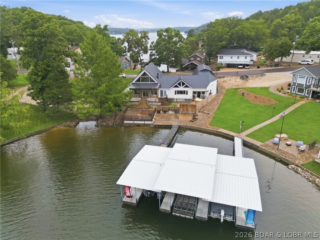 Imagine the possibilities. This isn't about buying someone else's dream home, it's about creating your own. The virtually staged photos showcase just a few of the possibilities this exceptional lakefront property offers. Think of it as a clean slate with freshly painted walls, ready for your personal style. Crafted with impressive Douglas Fir post-and-beam construction, this home features soaring vaulted ceilings, exposed beams, and a dramatic floor-to-ceiling stone fireplace that create the perfect foundation for a stunning rustic-modern retreat. Situated on a gentle, level lot in a protected cove, you'll enjoy easy access to the water and your shared dock with peaceful lake views. The spacious floor plan is ideal for entertaining, while the oversized garage offers ample space for vehicles, lake toys, hobbies, or the ultimate workshop. Above the garage, the expansive loft is ready to become a game room, bunk room, home office, fitness space, or additional storage. If you're searching for a lake home with personality, quality craftsmanship, and space that's hard to find at this price, this property is one you won't want to miss.