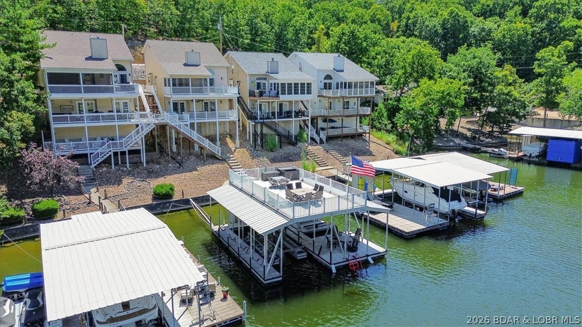 Set up for making the most of lake life, this 5BR/3.5BA home delivers plenty of space inside and out along with a fantastic cove location. Deep water and calm surroundings make this an ideal spot to spend the day swimming, fishing, kayaking and paddleboarding. The main floor with a soaring vaulted ceiling brings the kitchen, dining, living room and primary suite together for easy main level living. Multiple outdoor spaces include a screened porch, grilling deck and covered lower patio. Two bedrooms with a Jack & Jill bath are upstairs, while the walkout lower level offers another family room, 2 bedrooms, full bath and laundry. Just a short walk to the dock, where the huge rooftop deck becomes your outdoor gathering place with views stretching toward the main channel and the kids love taking a jump from the top!  Includes a 12x32 slip with hoist plus 3 covered PWC slips, including a double hoist. With nightly rentals permitted, this property works equally well as a personal lake escape, income-producing rental, or a combination of both.  Rental revenue projections are at 85K+ per year!!  Well maintained with newer LVP flooring throughout and a new roof in 2025.  Check it out TODAY!!