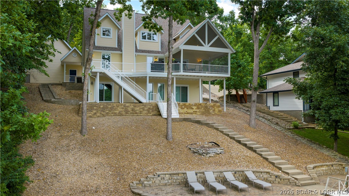 4 BED/4.5 BATHS/3600+ SQ.FT., 115' LAKEFRONT ON 2 LOTS WITH GREEN SPACE IN BETWEEN, STEEL AND CONCRETE DOCK, BOAT HOIST/PWC HOISTS,  & FURNISHED = THE PERFECT PACKAGE. Lake homes have a way of becoming the gathering place, and this one has the space to do it well. From the screened-in deck overlooking the water to the expansive lower level where everyone naturally ends up, there's room to spend time together without ever feeling crowded. The main level brings the kitchen, dining, and living areas complimented by a floor-to-ceiling stone fireplace, with the primary suite conveniently located on the same floor. Upstairs are two generously sized bedrooms with ample closet space and two full baths. The walkout lower level offers a lounge and game room with a second stone fireplace, fourth bedroom, full bath, half bath, and laundry room. Outside, the covered patio creates another place to gather, while a gentle walk leads to the private dock with a 14x24 slip and double PWC ports. The detached two-car garage provides additional storage, and the included vacant lot adds even more privacy. Lake frontage and acreage reflect both lots combined. Millionaire's Cove just got a little sweeter!