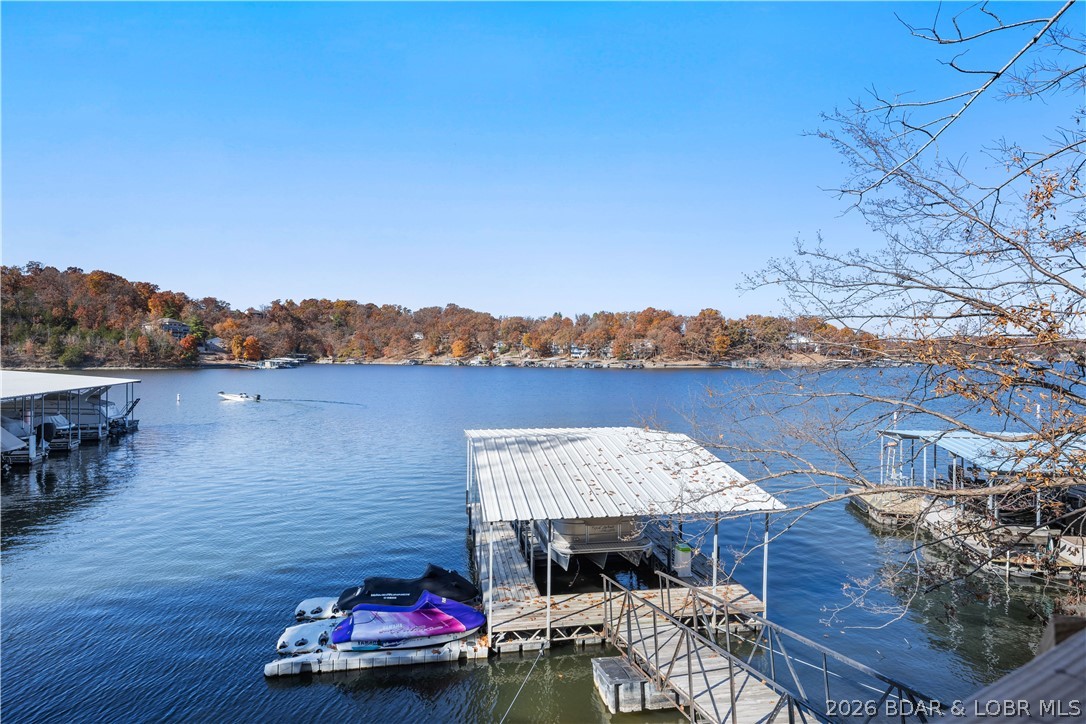 One-of-a-kind fully remodeled lakefront home on Mile Marker 3, perfectly positioned on an elevated lot with phenomenal water views in the highly sought-after Downing Branch Cove. This beautifully updated 4-bedroom, 3.5-bath ranch offers 3,136 sq ft of living space plus a 3-car garage with half bath and workshop area. Enjoy expansive outdoor living on two wraparound porches overlooking the lake. Renovations include all new flooring, completely remodeled bathrooms, a brand-new kitchen, new upper-level kitchenette, new appliances, new exterior doors, fresh interior paint, new roof, new storm doors, and steel beams/posts in the garage. Lake improvements feature a 12x26 one-well dock with hoist, two drive-on PWC lifts, and wet steps. Additional highlights include a guest-friendly studio area, gas fireplace, abundant natural light, and an inviting, meticulously updated interior. It is conveniently located near shopping and entertainment by land or water. This exceptional lake home is truly move-in ready and all of the updates have already been done for you—come see it today!