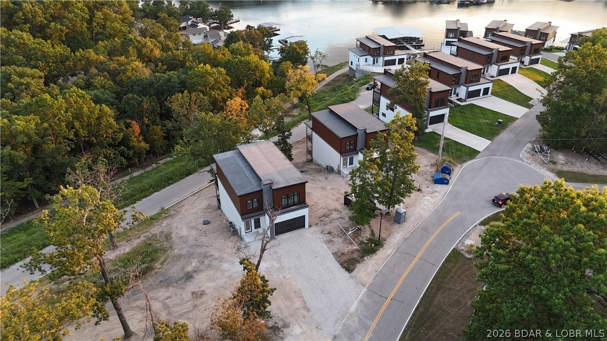 Lake views, lake access and brand-new construction come together at The Cove! This 4-bedroom, 3.5-bath home is currently under construction and will feature 2,936 sq ft of living space across three thoughtfully designed levels. Inside, you’ll find 10' main-level ceilings, a spacious kitchen with custom cabinetry, large center island, quartz countertops, tile backsplash and stainless steel appliances. The owner’s suite is designed as a relaxing retreat with a custom tiled shower, double vanity and walk-in closet. Covered outdoor living areas on each level provide plenty of space to entertain, unwind and enjoy the lake setting. Residents of The Cove enjoy a community pool and lake access through the community dock, with boat slips available for purchase. Conveniently located off Bittersweet Road near Shady Gators, waterfront restaurants, boating and entertainment, this is your opportunity to own a brand-new home in the heart of Lake Ozark!