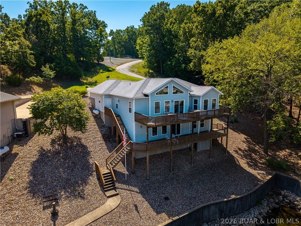 Enjoy the ultimate Lake of the Ozarks lifestyle in this updated 4BR, 3BA, 2,400 sq. ft. home in the sought-after Calvert development. Perfectly situated at the 26-mile marker, you are just minutes from premier golf, dining, and shopping, yet tucked away in a deep, protected cove with serene water views. The main level showcases a bright, open floor plan styled with durable luxury vinyl flooring throughout. The modern kitchen features quartz countertops, bar seating, stainless steel appliances, a pantry and seamlessly flowing into the living and dining spaces. Step out onto the expansive upper deck—the ideal spot for morning coffee or evening entertaining. Designed for hosting guests, the walkout lower level serves as a secondary entertainment hub, complete with a living area, wet bar, two bedrooms, and a full bath. Lakeside has a gentle double lot and smooth access to your private 2-well concrete dock—fully outfitted with a boat hoist, double PWC hoist & dock locker. Finished with an attached 2-car garage with built-in storage cabinets and abundant extra parking on a cul-de-sac. This move-in-ready property delivers effortless lakeside luxury. Call today to see this gem!!