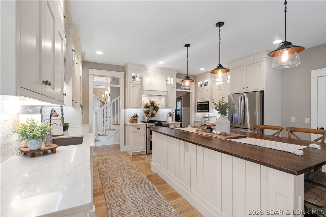 Opportunity at Osage National, this sprawling estate sits on two lots at the end of a quiet cul-de-sac and offers over 5,400 square feet of beautifully updated living space. Designed for those who love to entertain, the home features multiple gathering areas, a stunning remodeled kitchen with gas range, double ovens, custom cabinetry, & an inviting hearth room. The backyard feels like a private resort with a heated and chilled pool, screened porch, open-air deck, & fenced yard surrounded by mature trees for exceptional privacy. The thoughtful floor plan offers comfortable main-level living along with a private guest suite and abundant space for family and friends. Hardwood floors, two gas fireplaces, three HVAC systems, a flat driveway, oversized 3-car garage, mudroom with built-ins, & a new roof in 2025 add everyday convenience. Enjoy golf cart access to championship golf, Eagle View Bar & Grill, the community pool, & all the amenities that make Osage National one of the Lake's premier communities. Minutes from nearby marinas, this is a rare combination of luxury, privacy, and lifestyle that's difficult to replicate.