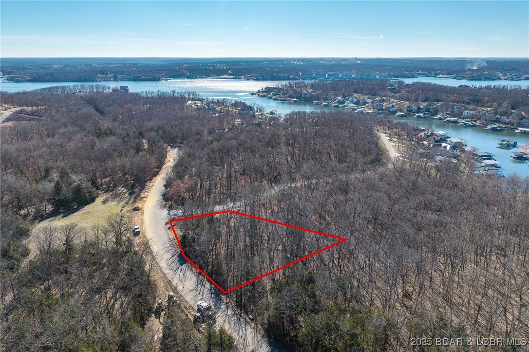 Surrounded by mature trees and natural Ozarks beauty, this wooded lot at The Villages at Shawnee Bend offers a peaceful, private setting within one of Lake of the Ozarks’ most distinguished communities. From the moment you arrive through the grand waterfall entrance, the neighborhood’s upscale character is clear. Residents enjoy access to a beautifully appointed clubhouse, resort-style community pool, championship tennis courts, and pickleball facilities, along with parks, and playgrounds. Paved roads and underground utilities make building seamless while preserving the natural landscape. Ideal for a custom home or lake retreat, this wooded homesite blends serenity, luxury, and an active lake lifestyle.