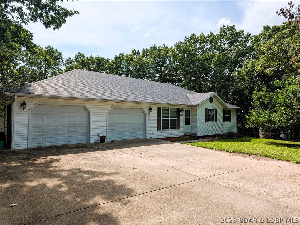 Welcome to this 4-bedroom, 3.5-bath home offering oversized living spaces, abundant storage & flexible floor plan. Double lot in Camelot Estates.  Step inside to discover a stunning great room with vaulted ceilings, rich wood flooring & open dining. Spacious kitchen for the aspiring home chef, abundant wood cabinetry & counter space, SS appliances, gas cooking. Laundry room & half bath .Main-level suite offers walk-in closet shower & jetted tub. One of the standout features is the bright & inviting sunroom just off the kitchen surrounded by windows to spend a morning watching birds or an evening enjoying the sunset through the trees. Finished lower level offers versatile floorplan & 4th bedroom, full bath, family room &  utility room & sunroom. Convenient dog door to fenced yard. Car enthusiasts, boaters &  hobbyists will appreciate the attached finished oversized 3-car garage & workshop area with a large concrete driveway. Utility garage has more storage. Recent updates include HVAC, water softener, water heater & new roof on the way. $40 month offers amenities,2 swimming pools, clubhouse, playground, boat ramp, fishing dock, tennis courts & more. Offering $5,000 carpet allowance.