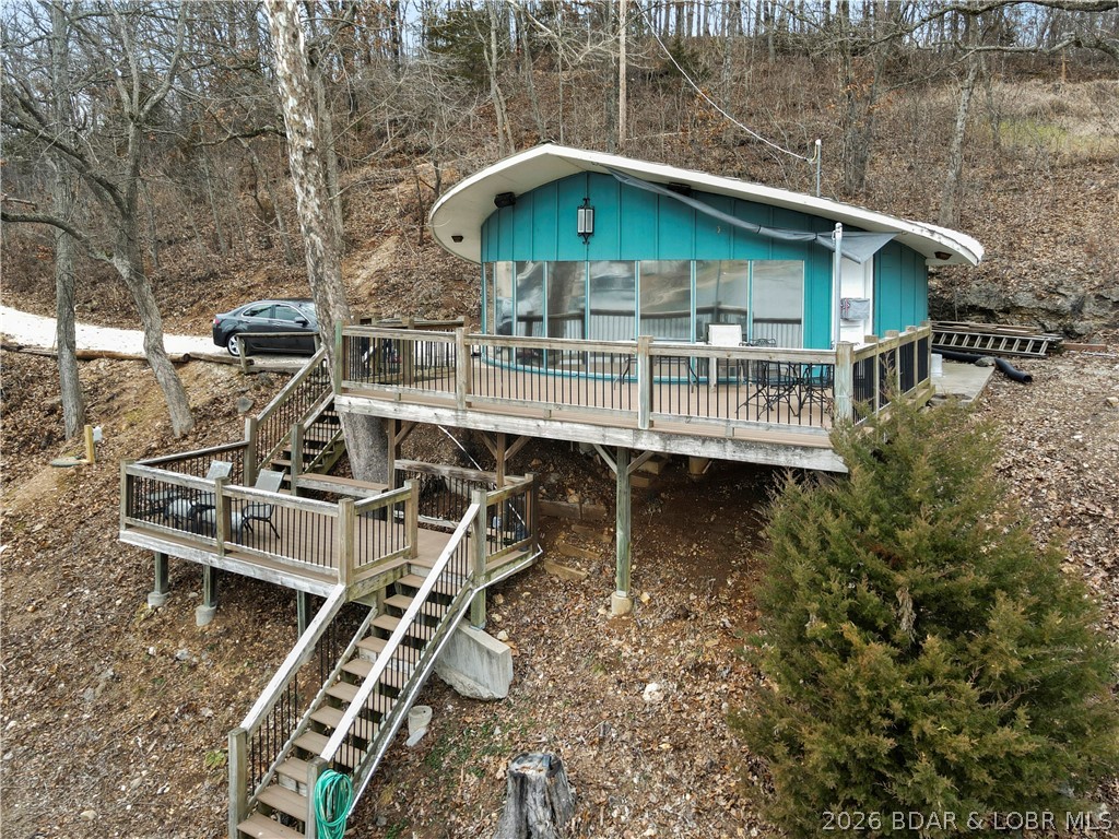 Rare opportunity at the 5 MM offering 237’ of beautiful shoreline in a huge, wide cove with deep water and outstanding views. Properties like this simply don’t come along at this price point. The setting is the real magic — expansive water frontage, room for additional docks, and endless development potential. With Rocky Mount central sewer in place, the options are wide open: build another home alongside the existing cabin, tear down and create multiple residences, or hold as a premier investment site.
The current 3BR lake cottage (844 sq ft) is quirky, fun, and full of character. Built-in queen over queen bunk setups allow it to sleep a crowd, and the entire lakeside is a wall of windows — giving it a one-of-a-kind “lakeside spaceship” feel. Being sold turnkey, it’s ready to use, rent, or redevelop immediately.  Home currently features a 2-well dock with room for expansion. Whether you’re looking for an affordable way onto the lake, a strong rental play, or a prime development tract, this property offers flexibility that’s hard to find.  All of this for under $400,000 on the beautiful Northshore of Lake of the Ozarks.