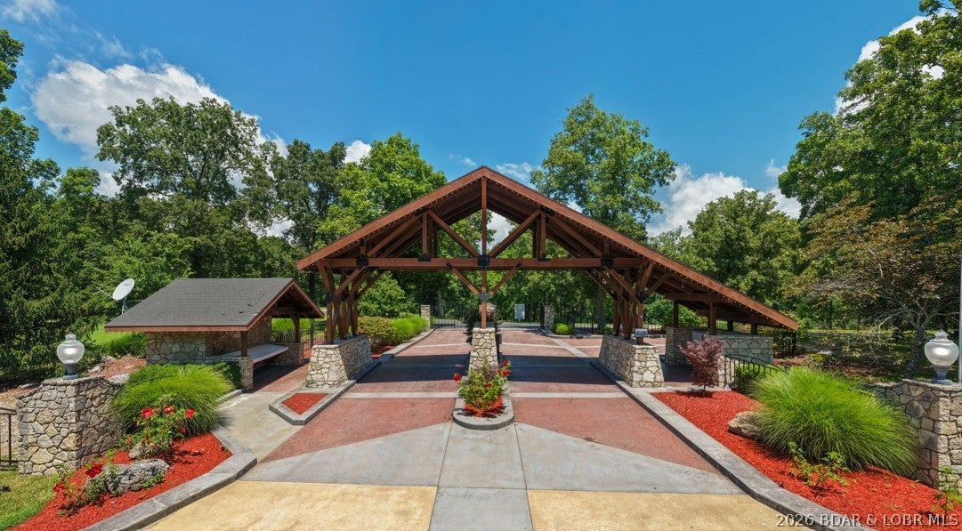 Home sale includes $75,000 cash due to buyer at close for rental income or can be used towards garage allowances. New construction, 5 private acres, gated entry, and resort-style amenities. Located in a luxury community next to Old Kinderhook, the 4-bedroom, 3-bath home offers 2,400 square feet and flexibility as a full-time residence, second home, or short-term rental. The open-concept main level features vaulted ceilings, generous kitchen counter space, the primary suite, a second bedroom, and an additional full bath. The lower level includes a second living area, two more bedrooms, a third full bath, and laundry. Enjoy the surrounding nature and wildlife from the large wraparound deck or covered lower patio with hot tub. Flat parking and ample acreage provide room for a future shop. Community amenities include a new clubhouse, indoor and outdoor heated pools, fitness center, spa, pickleball courts, maintained streets, and a convention center under construction. Minutes from Camdenton Square, Ballparks National, golf, and popular dining. Furniture, appliances, golf cart, and hot tub are included. Community roads are planned to be paved after construction is complete.