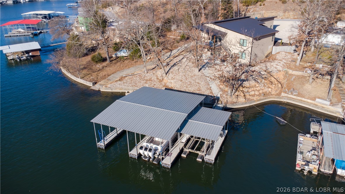 Welcome to luxury lakefront living with this contemporary home, custom-built in 2022 and situated on a lot in a prime Osage Beach location. This ~3,900 sq ft masterpiece features 6 bedrooms, 4 full baths, 2 half baths, and an oversized 2-car garage with a sleek standing seam metal roof. Designed with premium finishes throughout and offered turnkey in a calm, protected cove. The standout feature is the private living quarters, complete with its own entrance, kitchen, walkout, and laundry—perfect for potential Airbnb rental income, mother-in-law quarters, or accommodating extended family. Steps away you’ll find a custom-built 3-slip boat dock (14×40, 12×40, 12×18) situated in deep water for year-round lake access. The gently sloping lot provides easy access to the dock and lake. The home is equipped with 400-amp service, 100 amps dedicated to the dock, and a 50-amp EV charging plug in the garage.