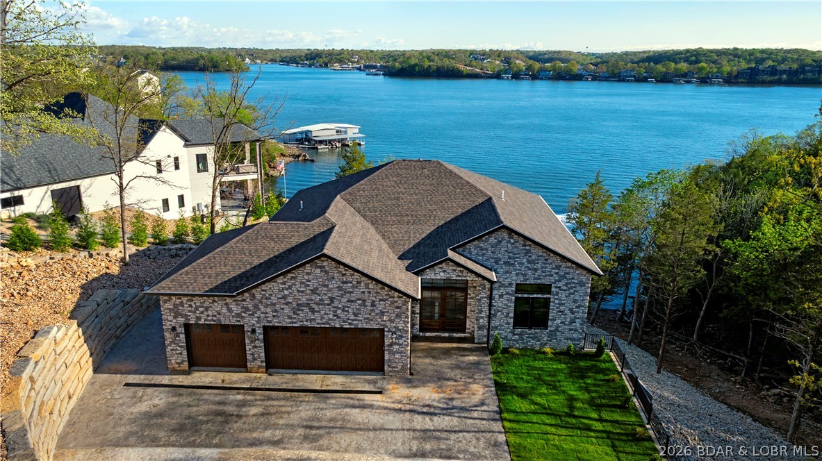 LAKE OF THE OZARKS - No home on Forest Trace has ever closed under $5M. This exceptional Villages at Shawnee Bend lakefront home offers 6 bedrooms and 6 baths, including 3 private lakeside master suites — creating the perfect retreat for family and cherished guests. Thoughtfully designed for comfort and connection, it features rich hardwood floors, soaring vaulted tongue-and-groove ceilings, and walls of windows that frame breathtaking main channel views and glowing sunsets. The open-concept living space is warm yet refined, showcasing high-end appliances, custom cabinetry, and elegant finishes ideal for gathering and entertaining. A dedicated entertainment area invites movie nights and relaxed evenings together. Step outside to expansive patios and inviting lounging spaces, complete with a poolside kitchen and lakeside firepit — perfect for sunset dinners and morning coffee by the water. Lush landscaping enhances privacy while embracing panoramic lake views. With a large cruiser dock providing effortless water access, every day brings boating, swimming, and unforgettable lakeside memories. This is more than a home — it’s where life slows down and memories are made.