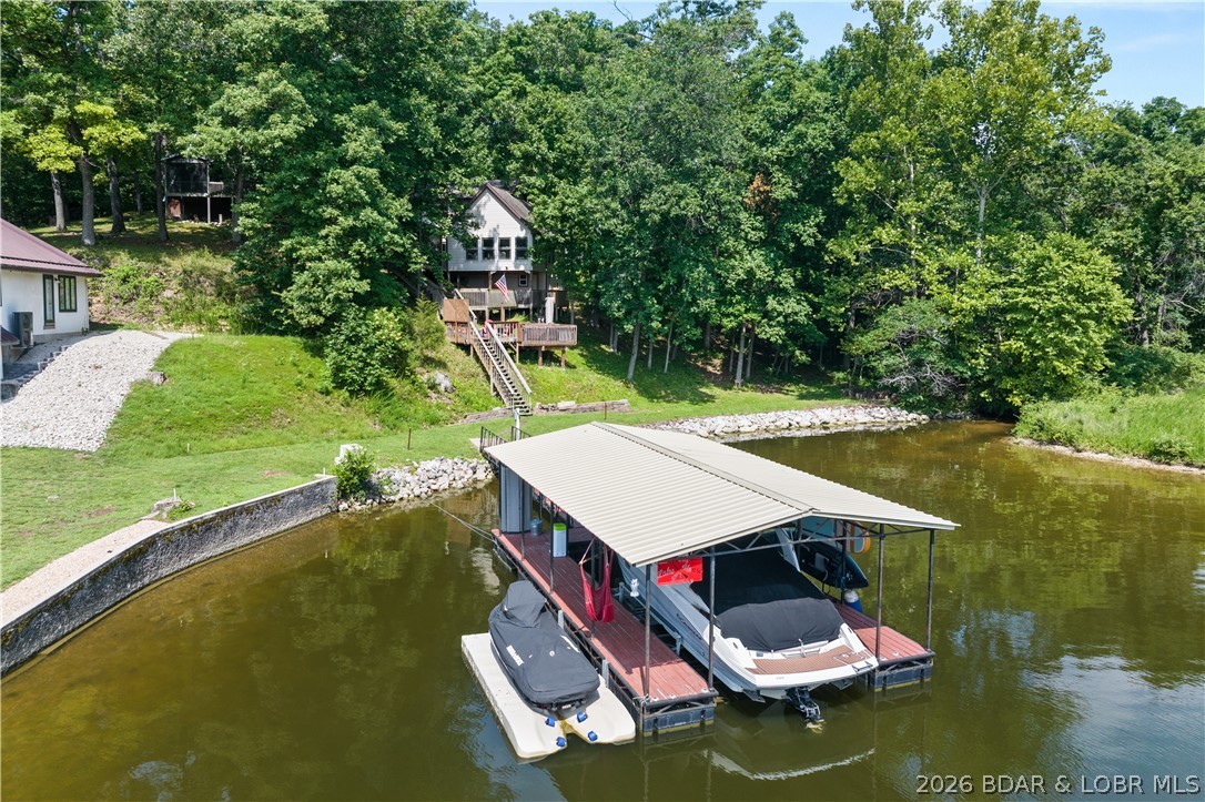 Discover peace and tranquility in this stunning lakefront home, nestled on a 1.62-acre lot at the 3MM in Rocky Mount within Jackson Branch Cove at Ozark Shores. Abundant wildlife & a beautiful, serene creek frame this 4-bedroom (2 nonconforming), 2-bathroom sanctuary. Step inside the expansive 1,465 sq ft open floor plan, where windows floods the interior w/natural sunlight. Meticulous attention to detail defines the exquisite remodel, showcasing vaulted ceilings, (LVP) flooring, newer drywall, and newer windows. Cozy up by the kitchen's inviting gas fireplace, complete w/KitchenAid appliances, or unwind on the fully screened-in porch. The upper level features an office nook overlooking the living room, a second bedroom, & a primary bedroom served by a full bath with a sleek seamless glass walk-in shower. Outside, enjoy multiple decks, a newer driveway, newer septic, & a relaxing 2022 Bullfrog hot tub. Your private waterfront haven includes newer rip rap & an exceptional dock featuring a 10'x30' boat slip, 2023 boat lift, drive-on PWC lift, & a newer dock roof. Prime location near local hot spots, so hop in your boat & explore today! *See rental revenue projection.