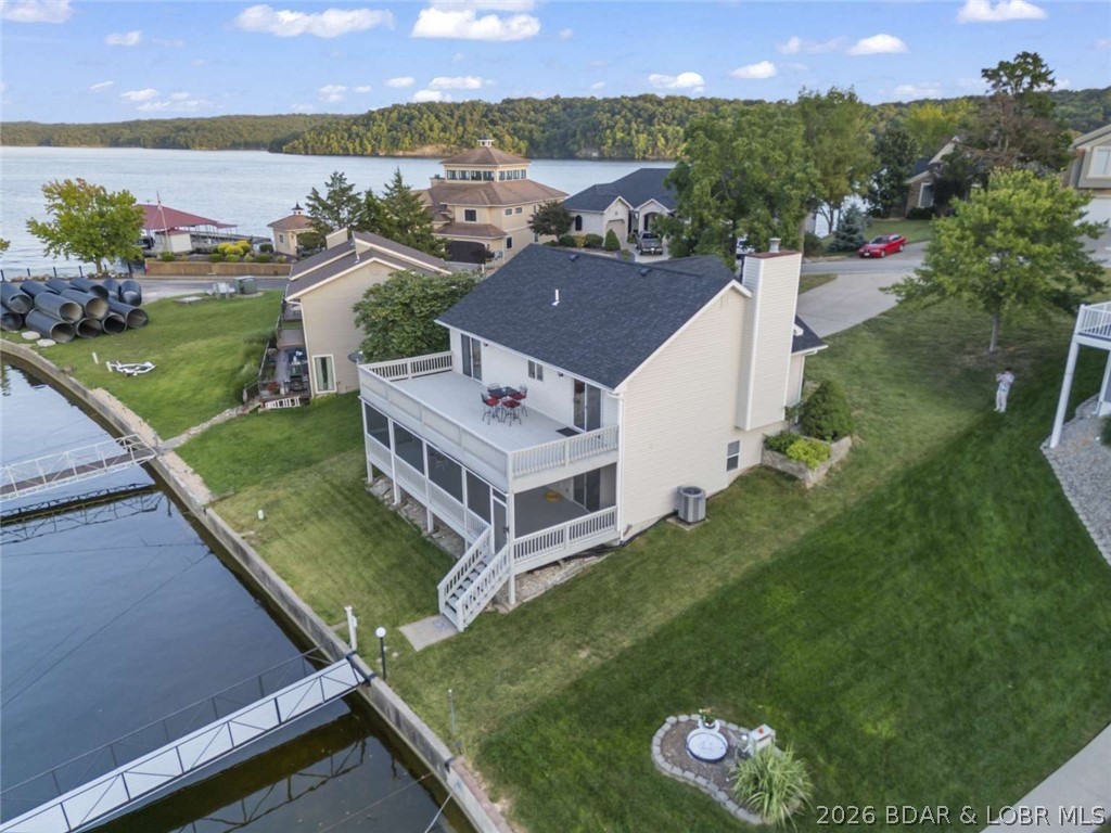 Rare lakefront gem offering a prime location by land and water at the 1.5-mile marker of the Grand Glaize Arm—less than a mile from Osage Beach Parkway with quick access to dining, shopping, entertainment, and Lake Regional Hospital. Enjoy a private dock with boat lift in a deep-water, no-wake cove with no through traffic—perfect for swimming and fishing. Deep water allows year-round boat use, with room to expand the dock (confirmed by Ameren) and nearby access to additional slips at the Moorings Yacht Club. Two large decks span the full length of the home with an open upper deck and covered, screened-in lower deck. This 3-bedroom, 2.5-bath home features vaulted ceilings, main-level living with a primary suite, and a spacious lower level for guests. Well maintained with updates including a new roof (2023), new siding (2024), updated kitchen, and new lower-level flooring (2021). Don’t miss this premier Osage Beach opportunity.