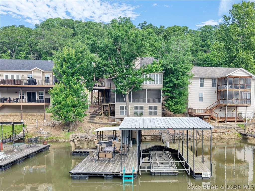 This fully furnished lakefront home is perfect for full-time living or as a successful vacation rental investment. The main level offers true one-level living with soaring vaulted ceilings and a wall of windows showcasing stunning main channel views at the 23MM while filling the home with natural light. Featuring 5 bedrooms and 3.5 baths, the oversized kitchen boasts custom cabinetry and opens to a spacious four-seasons dining area overlooking the calm, protected cove. The primary suite includes a private ensuite bath, while the upper level offers two additional bedrooms with a shared bath. The large composite deck off the kitchen is ideal for grilling and entertaining. The lower level features a second living area, wet bar, storage, plus an additional bedroom and bath for guests. A newly completed lakeside sunroom creates the perfect game or party space. Enjoy the oversized dock with a covered 14x36 boat slip and PWC slip (#16,000lb hoist available for additional cost) Convenient to Hwy KK amenities like: Margartiaville, Marinas, Waterfront Bars, Fine Dining, Golf Course and more! Yet nestled in peaceful Harbour Ridge—this is lake living at its best.