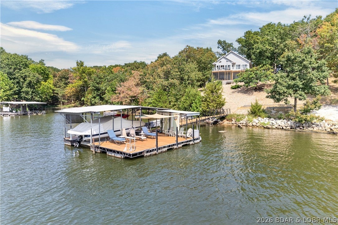 Lake Life on a whole new level! With 7+ acres and over 500 ft of shoreline, the combination of complete privacy, flat easy-access drive, and amazing lake views is insanely rare. Designed, built, and carefully maintained by its original owners, the 2017 home has a thoughtful layout made for everyday functionality—featuring main-level living, a spacious pantry, and a fenced yard for pets.
It’s built for entertaining with oversized windows showcasing the view, a second living room with a wet bar (projector, 100" screen, + surround sound!), a large screened-in porch, and a lakeside fire pit. A concrete sidewalk leads down to the boat dock featuring a 10x30 slip, 6,500# boat lift, and plenty of hangout space on the swim platform. The 53 Mile Marker location is ideal for swimming, water sports, and fishing. The detached 30x18 spray-foam insulated shop serves as a workshop plus a heated/cooled finished 4th bedroom or office! The land offers endless opportunity—potential to survey off a lakefront lot to build on or sell, build site by the road for another home shop, and room for trails through the woods. Hot tub, high-speed fiber internet, battery backup system, NO HOA, and more!