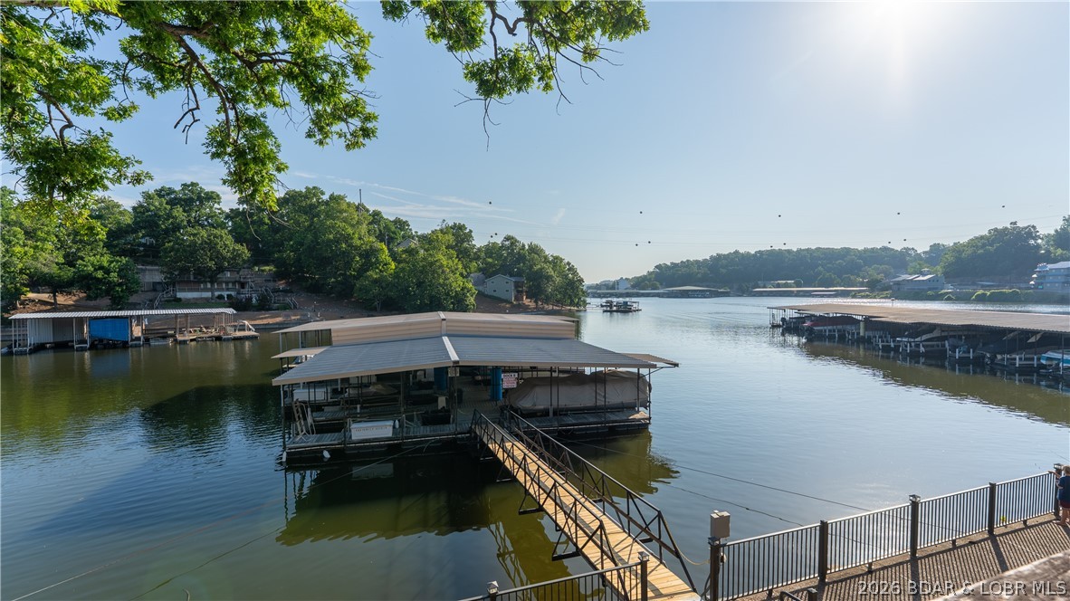 This rare lakefront villa-esque condo is one of only 2 units in the building, spanning 2,800 sq ft over two stories and owning the entire lakeside of the building. Fully remodeled in 2024 with $200k+ in upgrades, the main level features an open kitchen with lake views, spacious living and dining areas, a primary suite, 2nd bedroom, 2nd bath, laundry, a large deck (soon to be replaced), and a private entrance to the community pool. The lower level offers a dramatic two-story great room, 2 more bedrooms, a full bath, storage, and a building-width patio leading straight to the dock and swim platform. The unit includes one assigned parking space, a 10x24 slip with lift, and a PWC space. Located in Jennings Branch Cove at the 1mm, you're just a short boat ride from Lake Ozark Cafe, Bergers Marina, and Neon Taco, with easy access to the Strip and The Bagnell Dam. By land since you're at the top of Horseshoe Bend, you'll enjoy quicker access to town without the Bend weekend traffic. Baxter's, JB Hook's, JJ Twiggs, Sergio's, and the Historic Bagnell Dam Strip are all under 5 minutes away. This would make a great vacation Rental, second home ore even full time!