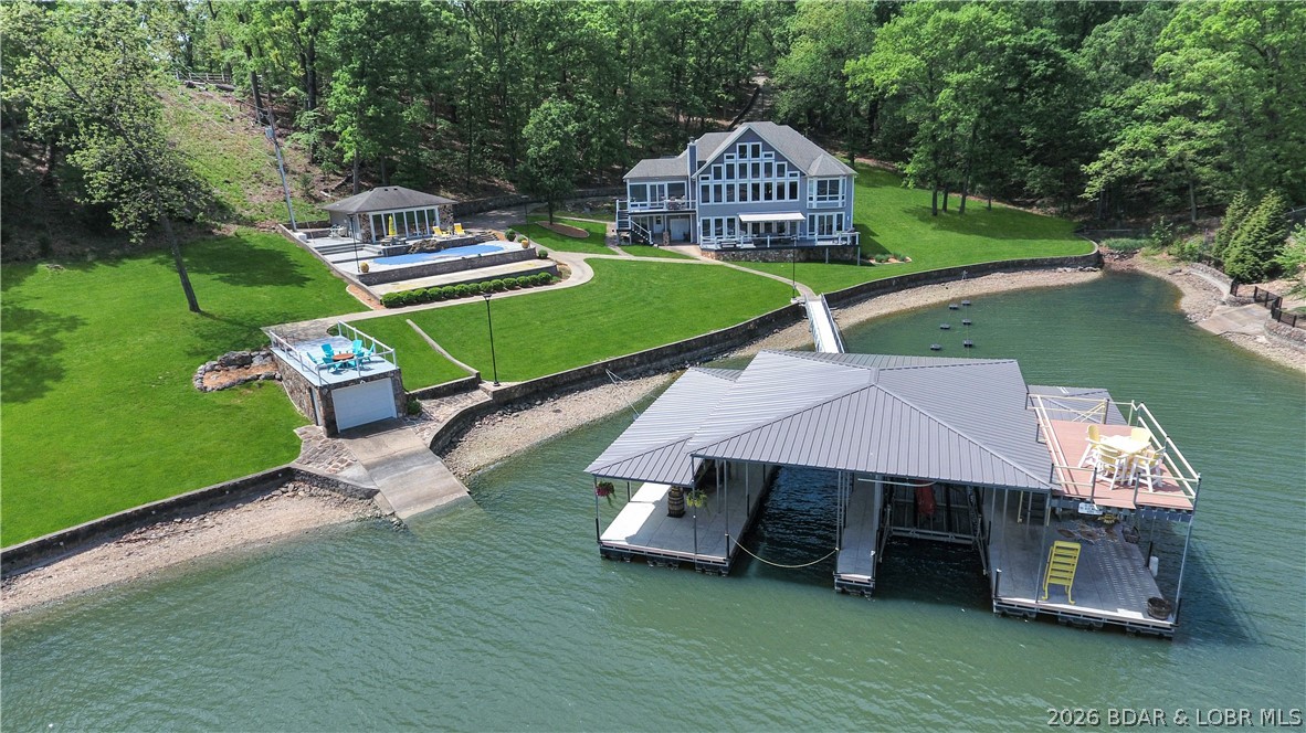 Nestled on 6 acres of pristine lakefront, this extraordinary estate offers an unparalleled combination of amenities and privacy. The main house with it's wall of windows overlooking the lake, features four spacious bedrooms, each with its own en suite, ensuring comfort and privacy for family and guests alike. The beautifully remodeled kitchen is a chef’s dream, boasting top-of-the-line Wolf appliances and a SubZero refrigerator, complemented by a butler's pantry with dog washing station. The estate also includes a charming guest cottage, perfect for visitors or extended family stays. Outdoors, you'll find a private pool and shuffle board court for relaxation and entertainment, while the boat dock features two 12x36 boat slips, a double PWC space with lift, wet steps, and a roof-top deck. A boathouse with rooftop patio offers spectacular views of the lake, and there's a private boat ramp as well. For car enthusiasts there is a 48x72 detached garage building and a second 20x39 detached garage providing ample space for vehicles, toys and storage. Situated in a serene cove location at the 18-mile marker, this one-of-a-kind property promises a luxurious lakeside lifestyle like no other!
