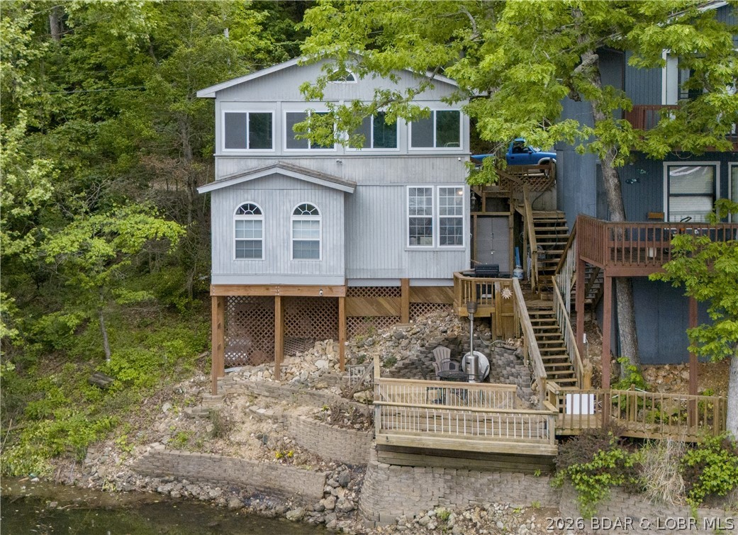 Discover peaceful lakefront living in this charming home tucked away in a quiet cove at the 6MM of the Gravois
Arm. With 3 spacious bedrooms—including 2 with stunning lake views—this property is the perfect retreat for
family fun or a relaxing escape. Enjoy a large eat-in kitchen, a three-season sunroom with new windows and screens ideal for morning coffee or evening sunsets, and a lake-level martini deck where you can fish, unwind, or watch the kids play in the calm cove waters below. Recent updates include new LVP on the lower level, new A/C system for year-round comfort, extended grilling niche, replaced outdoor wooden stairs, lighting, electrical & plumbing. The home sits on a quiet, dead-end road
with no through traffic, access to a shared dock featuring your own dedicated boat slip with lift,
plus an additional private PWC lift. Lovingly maintained and currently a successful short-term rental, this home
combines modern convenience with lakeside charm. Located in popular Indian Creek area close to restaurants,
marinas, and all the lake fun—while still enjoying your own relaxing get-away.