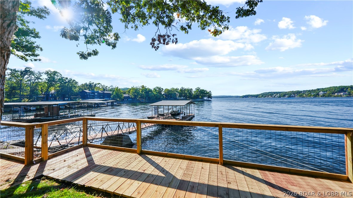 Some lake properties check boxes and some actually deliver, and 185 Betlo Drive at the 11 mile marker in Sunrise Beach is the kind of lakefront home that delivers. Sitting on 106 feet of Lake of the Ozarks shoreline with main channel views and some of the best sunsets on the water, this 3-bedroom, 2-bath home has the gentle lot and easy water access that buyers spend months searching for. The private dock has a large envelope for future expansion, the lakeside patio is built for entertaining, the detached insulated 2-car garage handles every lake toy you own, and the covered decks give you outdoor living space in every direction.  This home is getting a new septic tank next month!! Inside, large picture windows frame the water from both living areas, the updated kitchen features custom wood cabinetry with a turquoise tile backsplash and granite countertops, and the finished walkout lower level adds flexible space for guests. This is a ten-home enclave at the end of Highway TT where nightly vacation rentals are not allowed and the only people on the water are your neighbors. Franky and Louie's and Lake House 13 are minutes away by land or by boat.