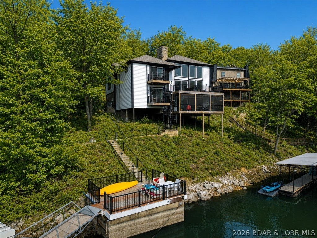 Exceptional lakefront investment opportunity in the heart of Osage Beach! Located at the 25MM within Tan-Tar-A/Margaritaville Lake Resort, this property is a proven performer for short-term rental income, or a perfect family getaway! Offering over 4,200 sq ft, this spacious home features 4 large bedrooms (three with two queen beds), 3 bathrooms, and a rarely seen open floor plan for the neighborhood. The beautifully updated kitchen and dining area flow seamlessly into a HUGE vaulted living room highlighted by a stunning floor-to-ceiling rock fireplace. The main level includes 2 bedrooms and 2 bathrooms, while the lower level offers 2 additional bedrooms, a full bath, and flexible entertaining space—ideal for large groups and rentals. Outdoor living shines with three decks, a screened porch, a permitted martini deck, and a private dock, perfect for soaking up the Lake lifestyle. Located in Tan Tar A Estates within the Margaritaville Resort complex, owners and guests enjoy amenities galore, making this a highly desirable rental destination. A rare opportunity to own a lakefront property that combines rental potential, prime location, and unforgettable Lake of the Ozarks living.