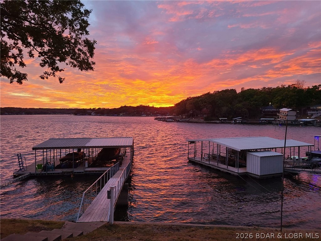 Lake living is easy in this beautiful home located in the highly desirable "O Road" area near Laurie at the 8MM of Lake of the Ozarks. Enjoy spectacular main channel views, as well as multiple outdoor living spaces. With paved roads all the way and just one step into the home from outside or the attached garage, access is easy. The main level features an open concept kitchen, dining, & large living room space with fireplace, primary bed and bath, & an expansive four-season room overlooking your lakefront. A Trex deck just off the kitchen & dining area provides the perfect spot to relax and take in the view. Upstairs, two guest bedrooms share a Jack-and-Jill bath & overlook the main living area below. The walkout lower level offers a large family room space with wet bar & updated half bath. Step outside to a covered patio with built-in seating that spans the length of the home. Just a few steps from the patio, you'll find a concrete dock with 14x36 and 10x26 slips, each with newer lifts along with a lounging area with wet steps to add to the lake fun. Whether you're looking for a full-time residence, weekend retreat, or short term rental, this home is ready for your  adventures!